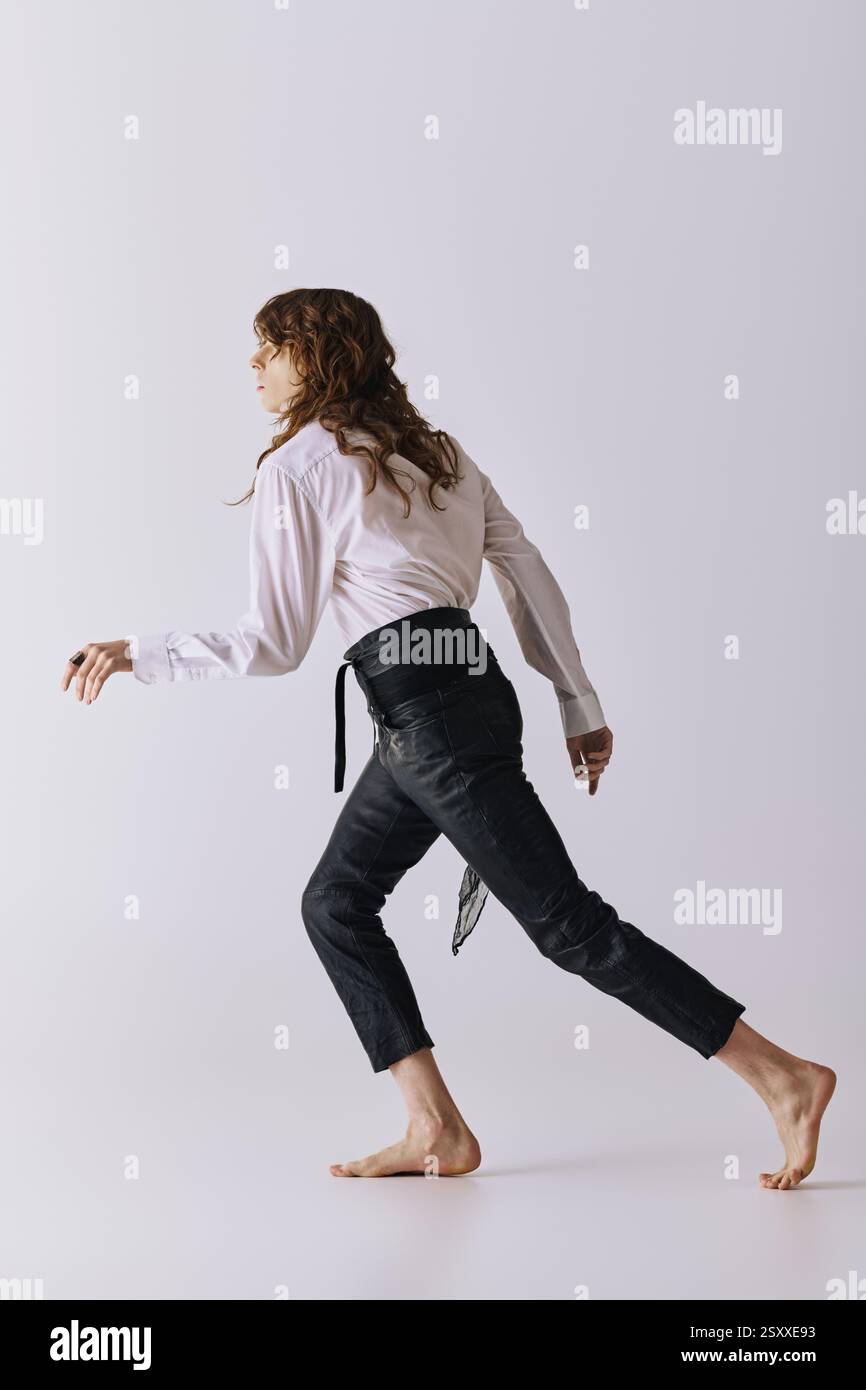 Un bell'uomo si muove con eleganza in uno studio chic, mostrando moda moderna e stile disinvolto. Foto Stock