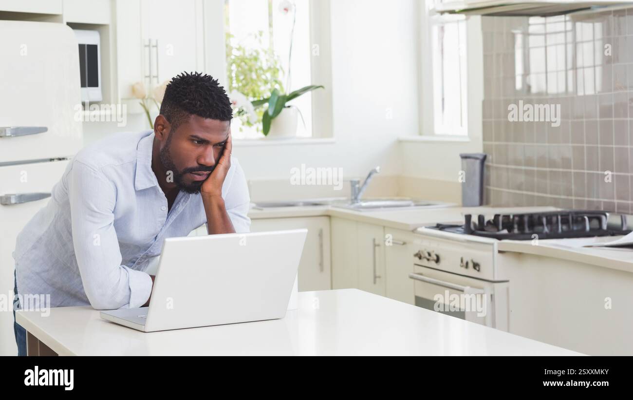 Uomo che lavora su un notebook in cucina, che si concentra sull'attività a casa, copia spazio Foto Stock