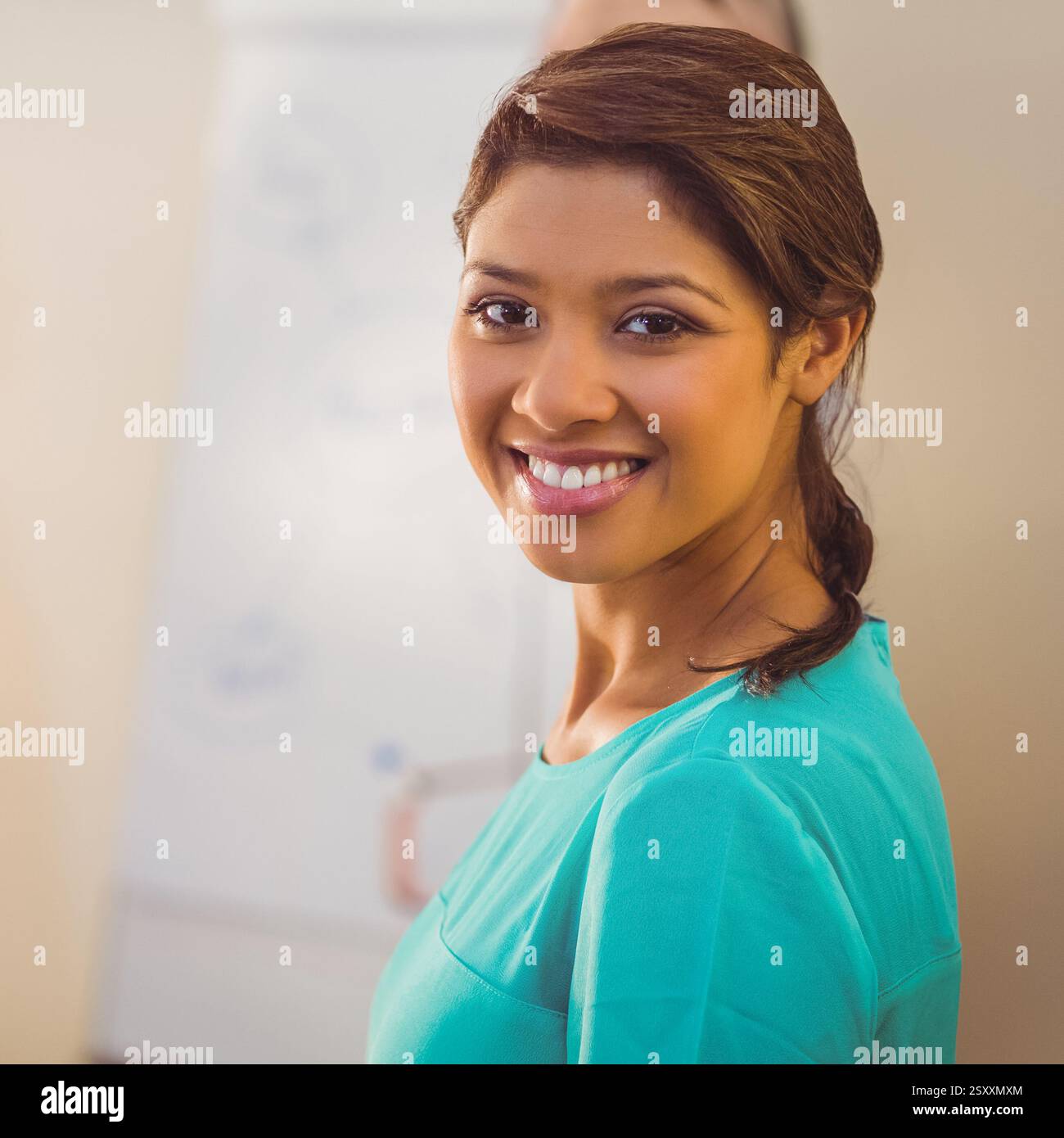 Donna sorridente in ufficio in piedi con sicurezza vicino alla lavagna, abbracciando il lavoro di squadra Foto Stock