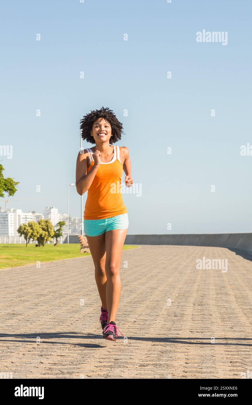 Donna che fa jogging sul lungomare soleggiato, si gode l'esercizio mattutino e l'aria fresca, spazio fotocopie Foto Stock