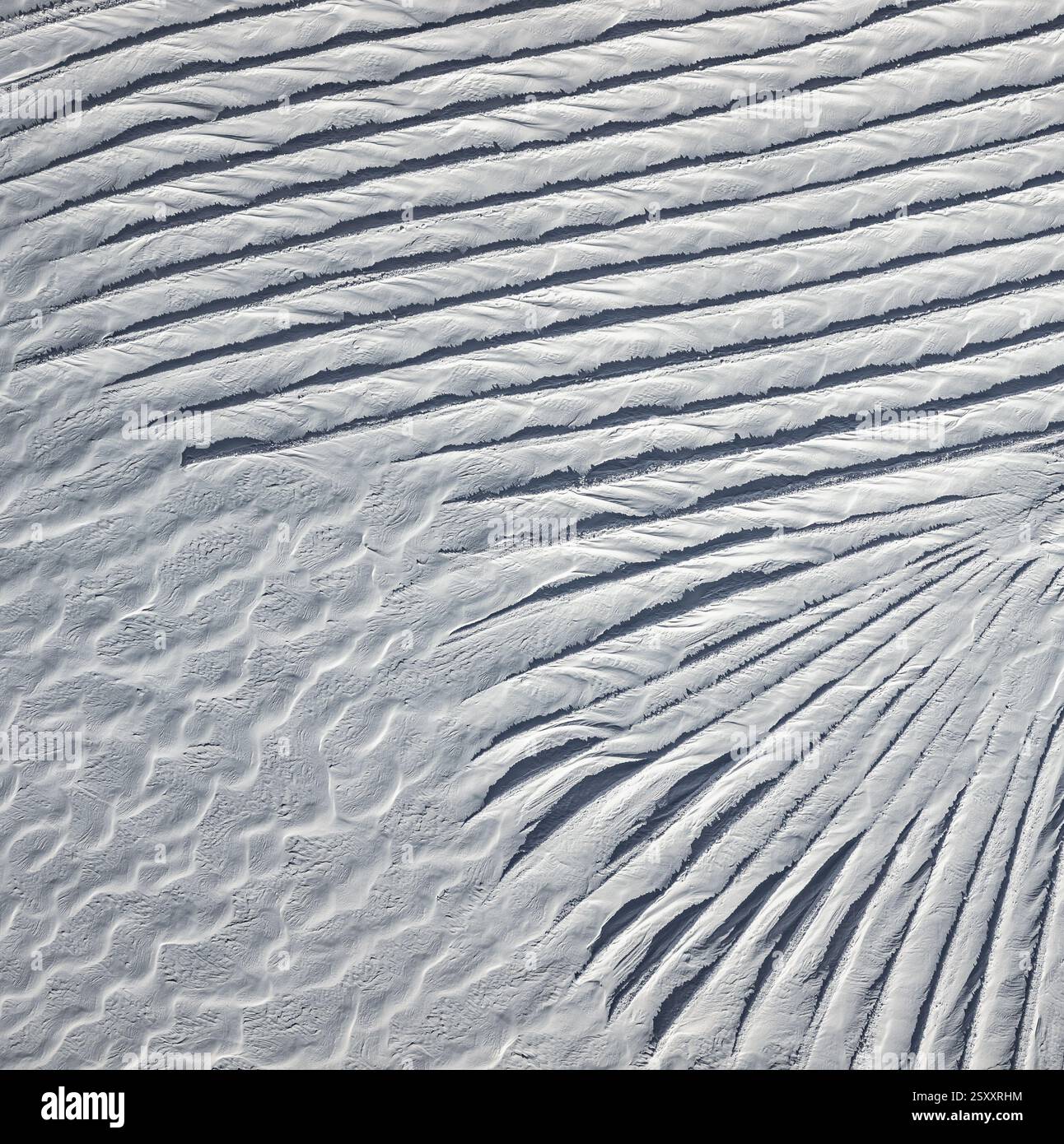 Una vista aerea delle intricate formazioni di neve sul Ghiacciaio 3000 nelle Alpi svizzere. Il vento ha scolpito la neve in un ipnotico schema di r Foto Stock