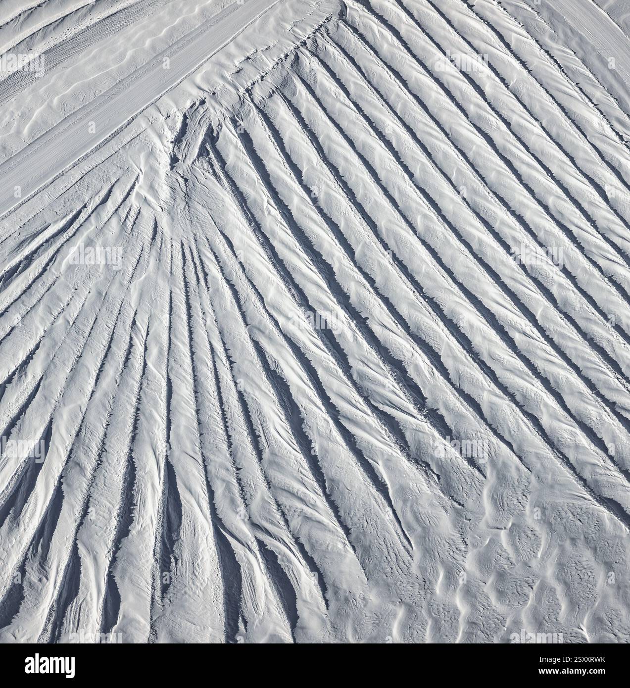Una vista aerea delle intricate formazioni di neve sul Ghiacciaio 3000 nelle Alpi svizzere. Il vento ha scolpito la neve in un ipnotico schema di r Foto Stock