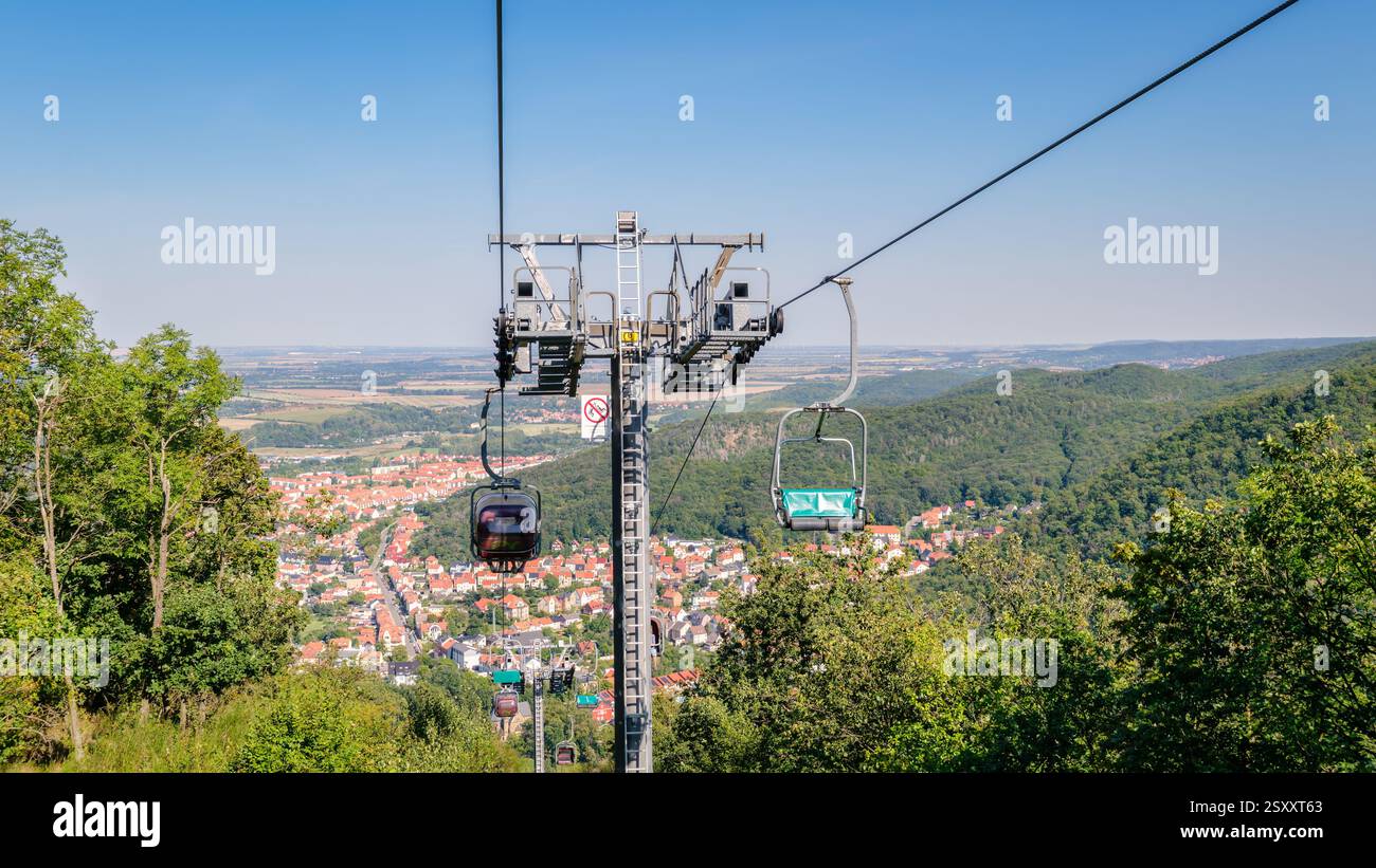 Thale, Germania – 27 agosto 2024: I turisti in sella alla seggiovia che collega Thale con la falesia di granito alta 403 metri Rosstrappe godono di una splendida vista Foto Stock
