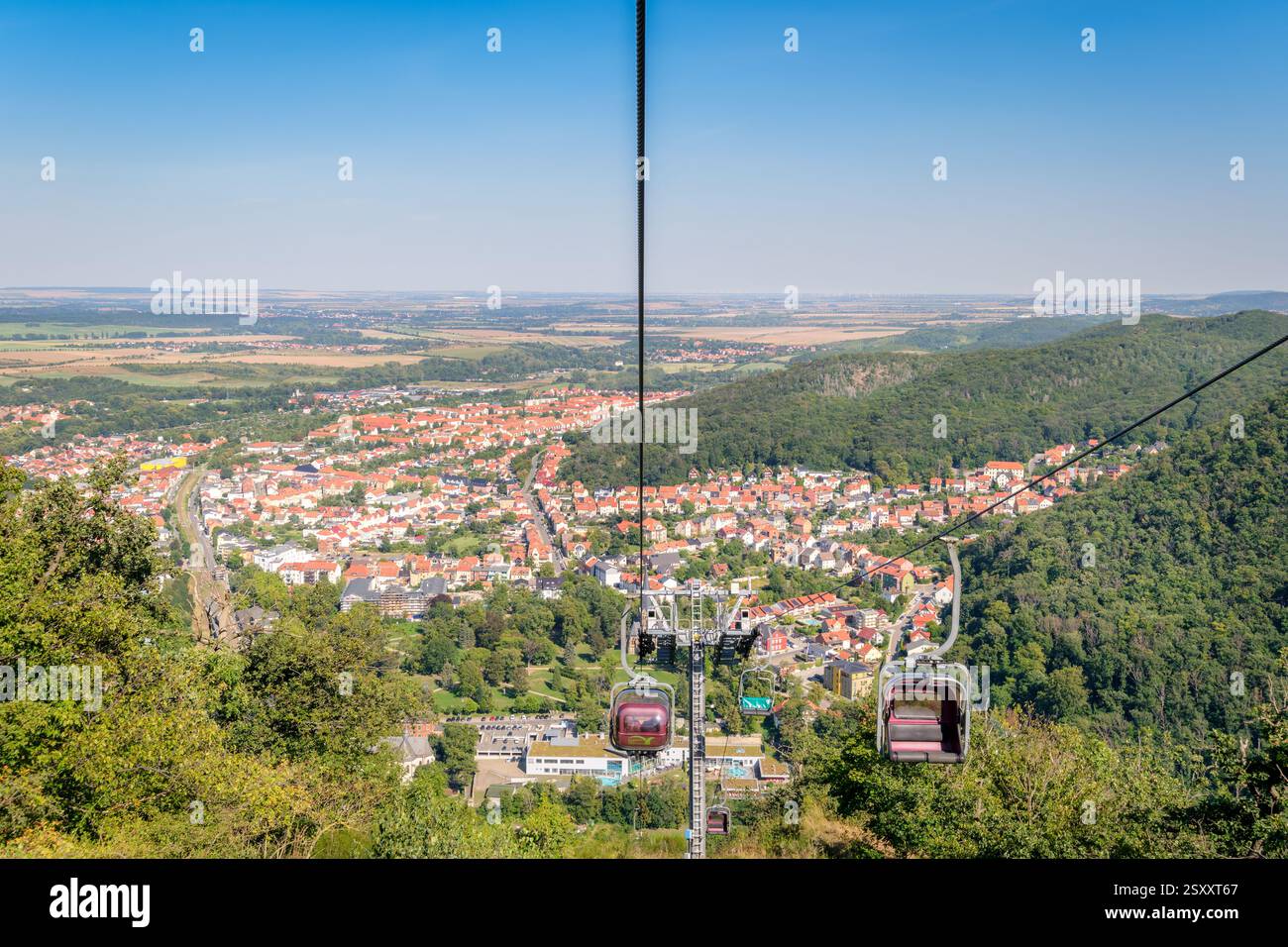 Thale, Germania – 27 agosto 2024: I turisti in sella alla seggiovia che collega Thale con la falesia di granito alta 403 metri Rosstrappe godono di una splendida vista Foto Stock