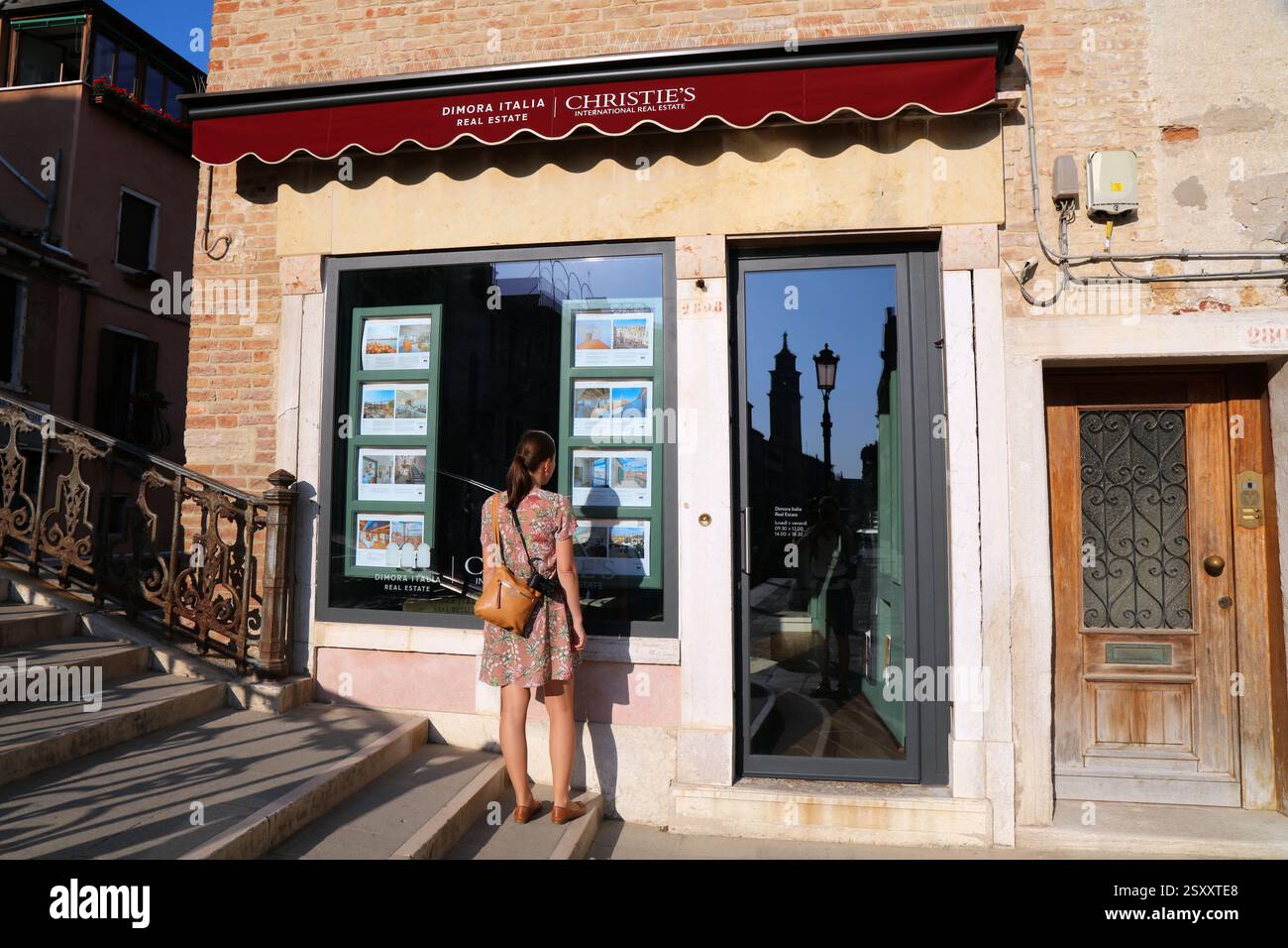VENEZIA, ITALIA - 21 MAGGIO 2023: Il turista legge gli annunci di agenzie immobiliari in Christie's International Real Estate a Venezia, Italia. Foto Stock