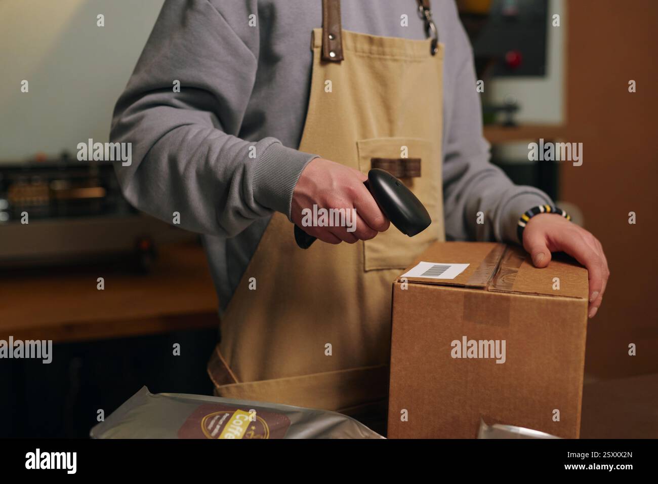 Primo piano medio di un lavoratore di fabbrica non riconoscibile che esegue la scansione di codici a barre su una scatola di cartone Foto Stock