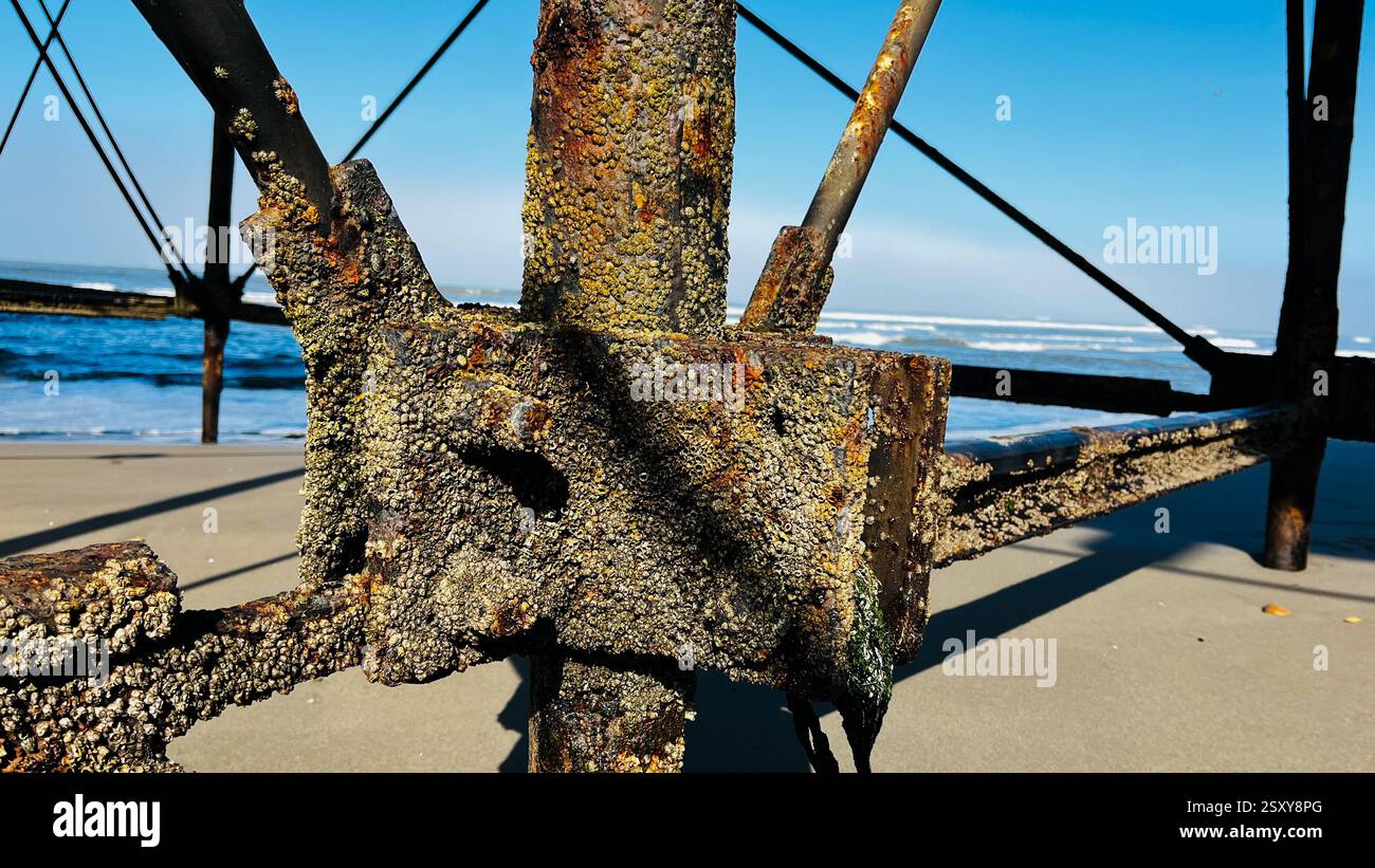 Vecchi pali di metallo arrugginiti sotto il vecchio molo che fronteggiano il tempo e la potenza della natura, acqua salata di mare e sole forte. Foto Stock