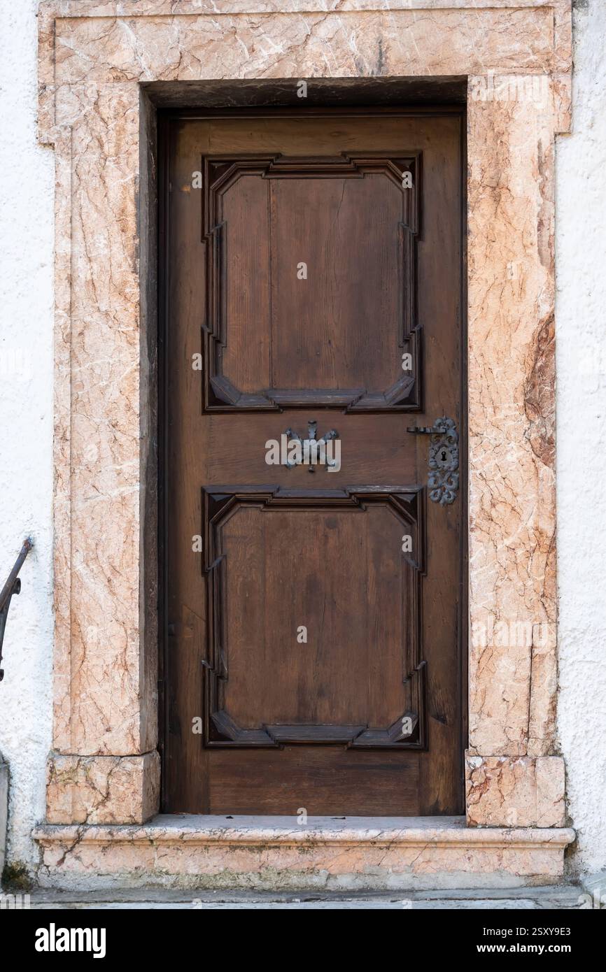 Porta antica in un edificio storico con effetto del tempo: Crepe nella pietra, legno scuro, maniglia in ferro battuto. Architettura europea Foto Stock