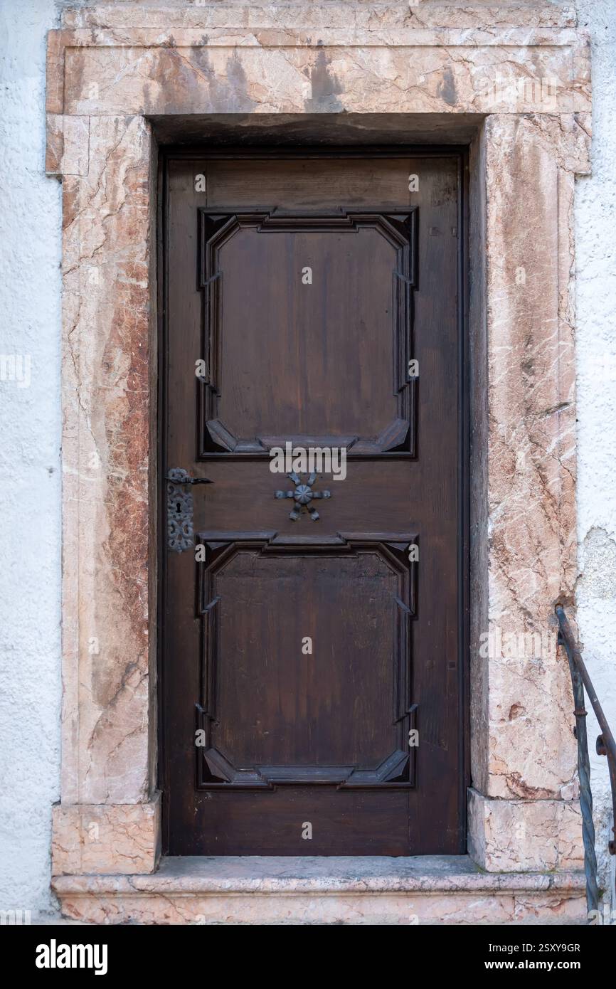 Antica porta in legno con elementi intagliati, costruita in una facciata in pietra. Design antico, atmosfera vintage, architettura storica Foto Stock