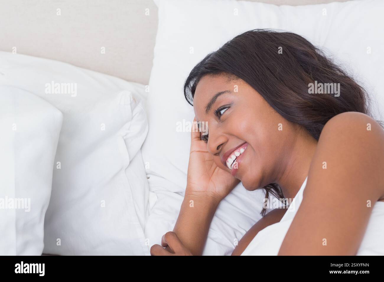 Donna sorridente che si rilassa a letto, goditi una tranquilla mattinata a casa, copia spazio Foto Stock
