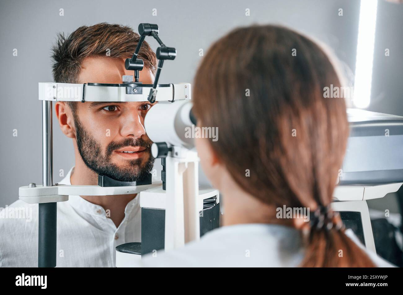 Visione dell'uomo controllata dal medico in clinica utilizzando uno speciale dispositivo optometrico. Foto Stock