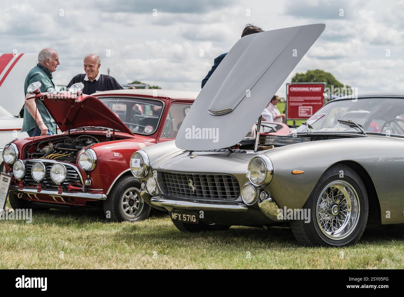 Tarporley, Cheshire, Inghilterra, 28 luglio 2024. La gente sta guardando una Ferrari 250 GT SWB e una Austin Mini Cooper a un incontro di auto d'epoca. Foto Stock
