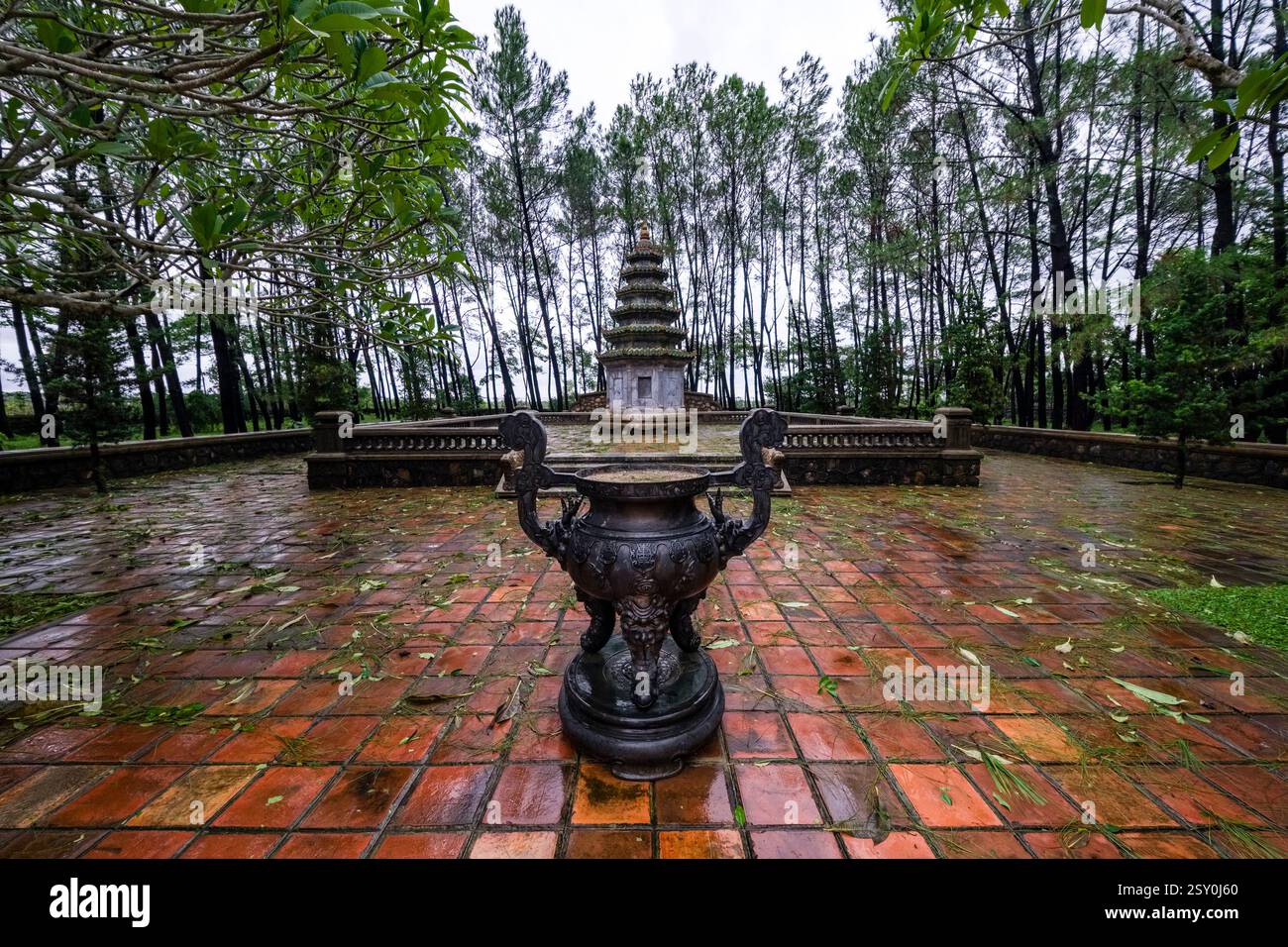 La costruzione di una piccola pagoda all'interno del complesso del Tempio della Signora Celeste, Chùa Thiên Mụ, visto su un grande vaso di ferro. Foto Stock