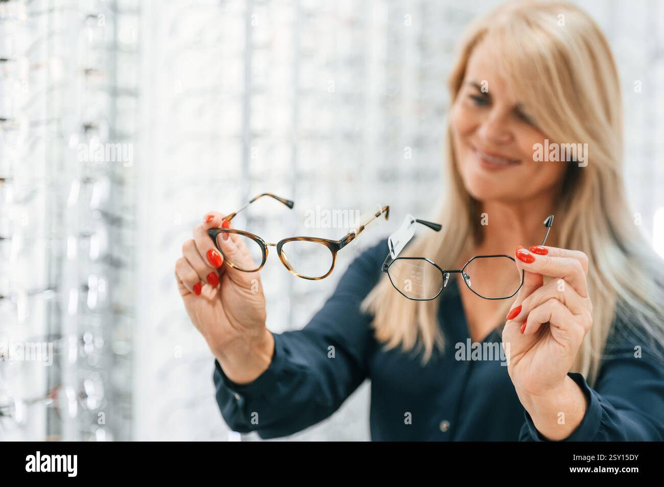 Donna che tiene gli occhiali in mano. Una visitatrice femminile è nel negozio. Foto Stock