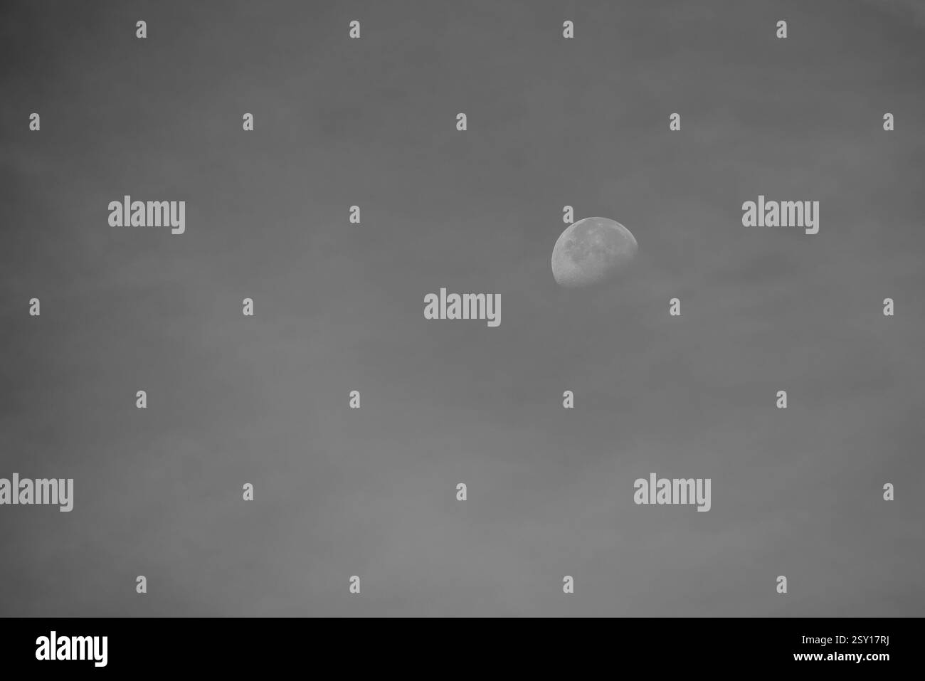 Luna vista durante il giorno contro un cielo blu in bianco e nero Foto Stock