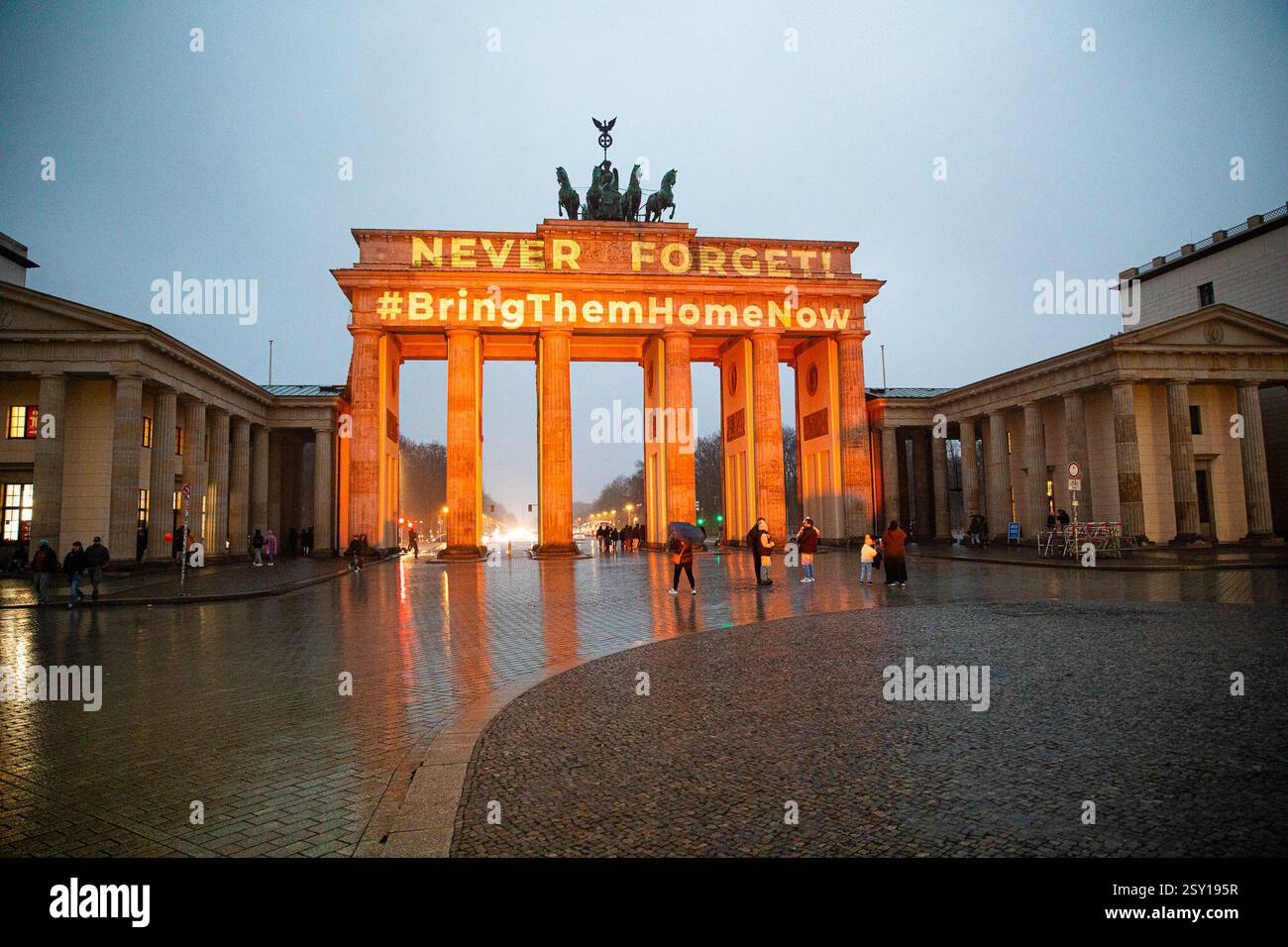 La porta di Brandeburgo a Berlino è stata illuminata di arancione mercoledì 26 febbraio 2025, mentre la folla si è riunita per piangere i membri della famiglia Bibas, che sono stati uccisi in cattività dopo essere stati presi da Hamas durante l'attacco del 7 ottobre contro Israele. Il tributo, un potente simbolo di solidarietà con Israele, ha attirato persone che hanno deposto fiori e palloncini arancioni in memoria di Shiri Bibas e dei suoi due figli, Ariel e Kfir. L'ambasciatore israeliano in Germania Ron Prosor ha partecipato all'evento, in piedi al fianco dei lutti mentre onoravano le vittime. (Foto di Michael Kuenne/PRESSCOV/Sipa USA) Foto Stock
