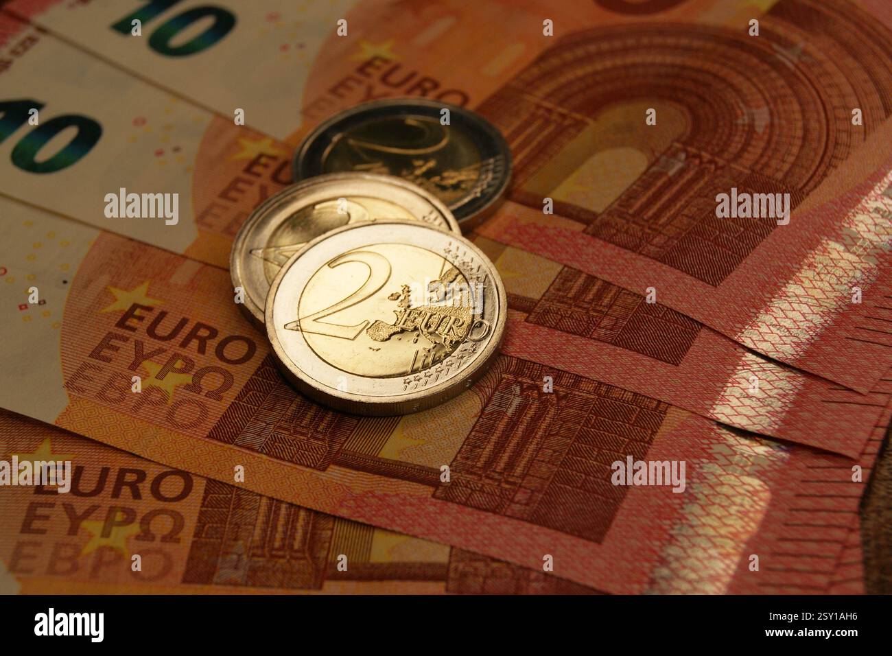 Nuove e brillanti monete da 2 euro su banconote da 10 euro. Valuta della zona euro. Foto Stock