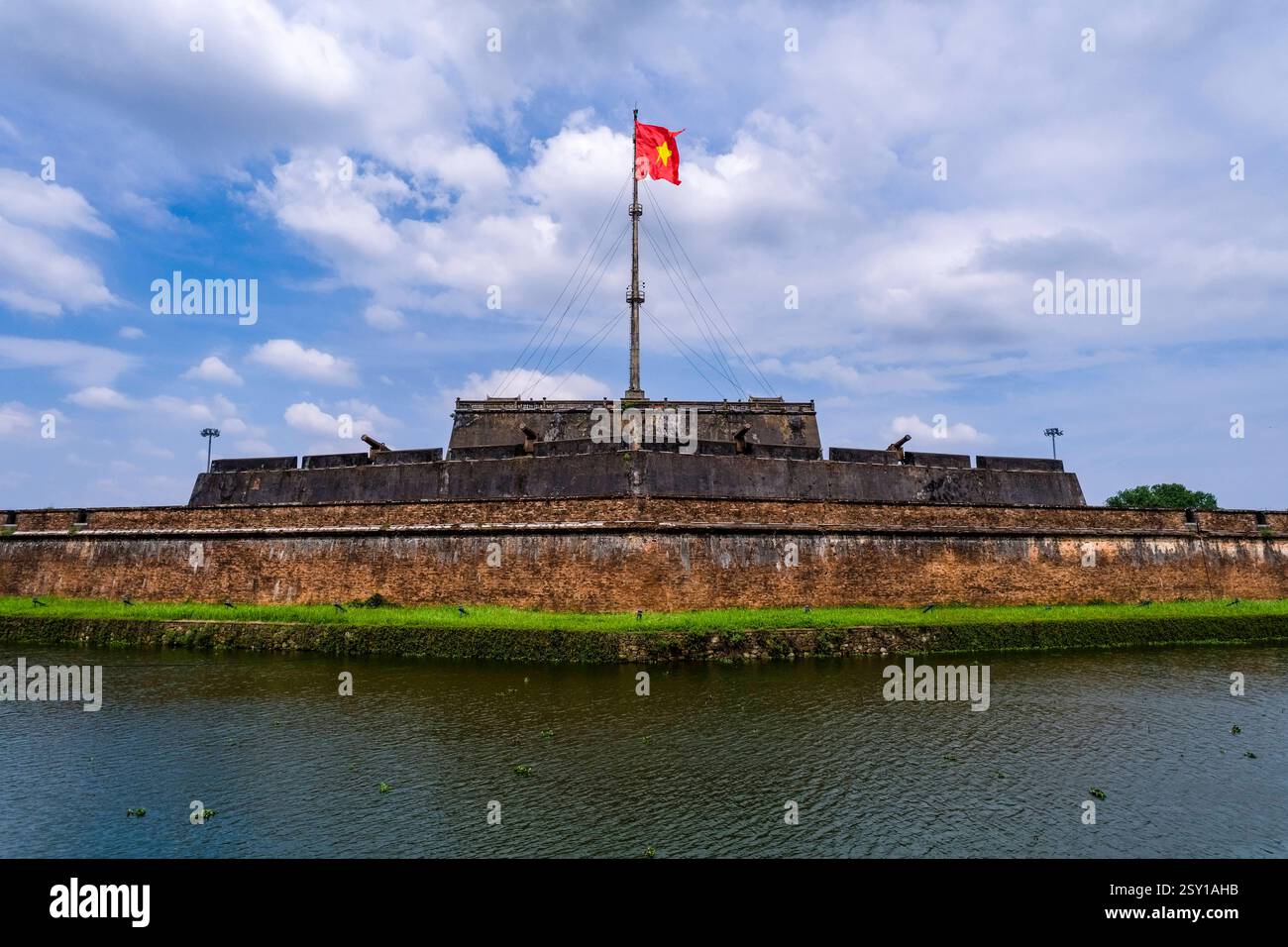La torre di bandiera, Ky dai, con la bandiera vietnamita sventolante fa parte della cittadella di Hue, HoÃ ng ThÃ nh, vista attraverso un canale d'acqua. Hue Thua Thien Hue Foto Stock