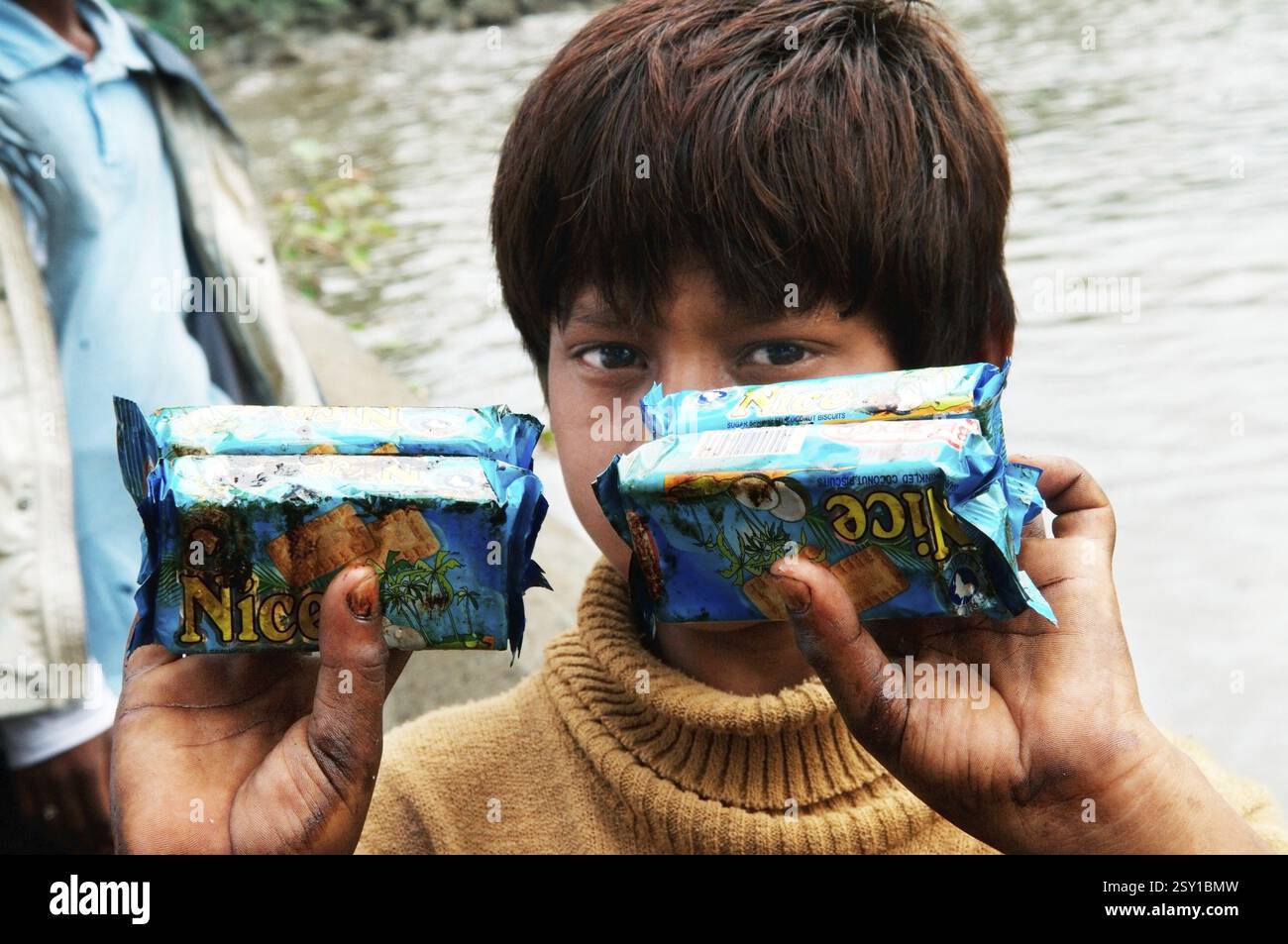 Ragazzo che mostra pacchetti di biscotti imbevuti di olio a causa della nave container chitra che si scontrano in mare a Mumbai, Maharashtra Foto Stock