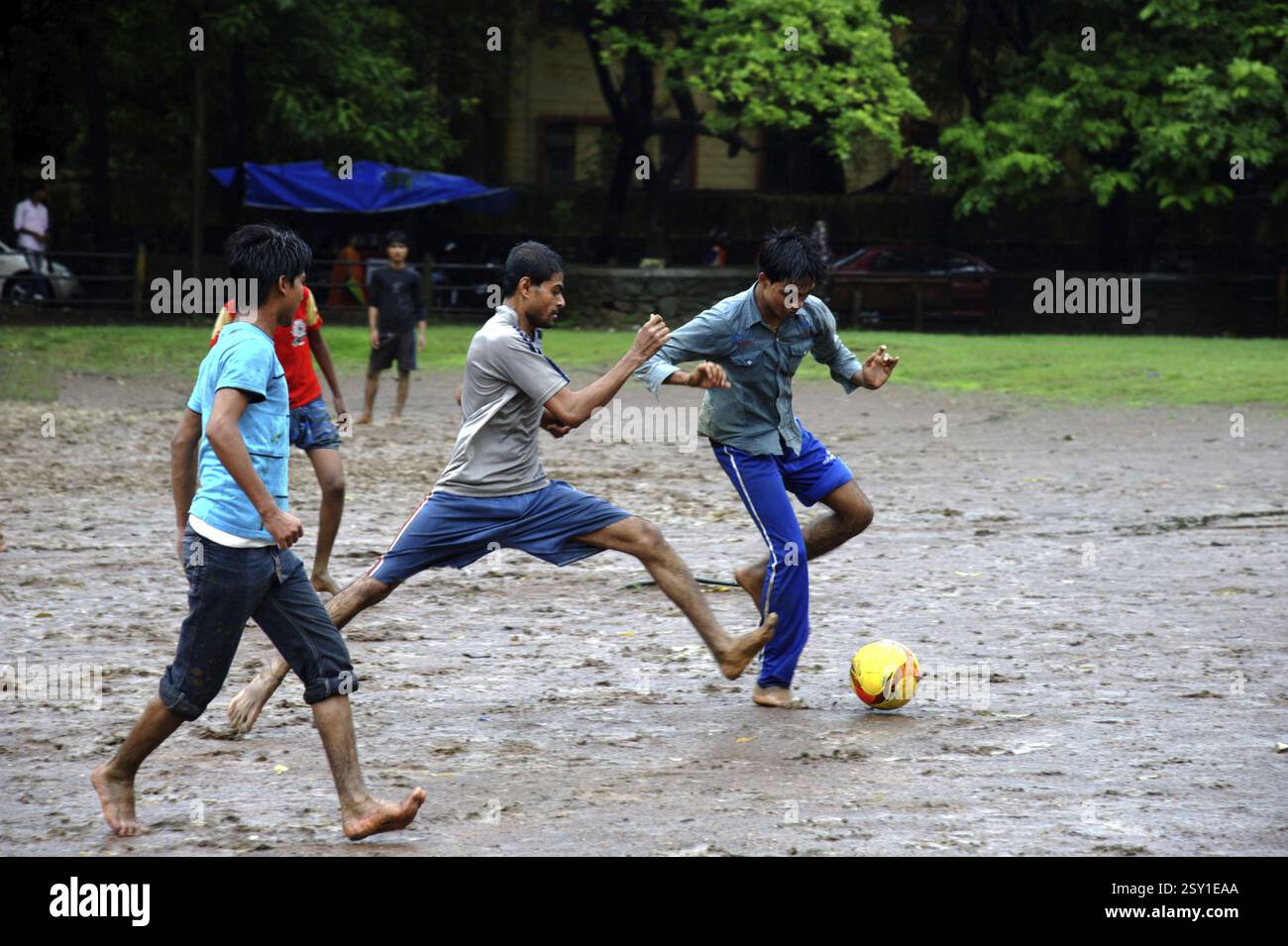 Ragazzi che giocano a calcio sotto la pioggia Foto Stock