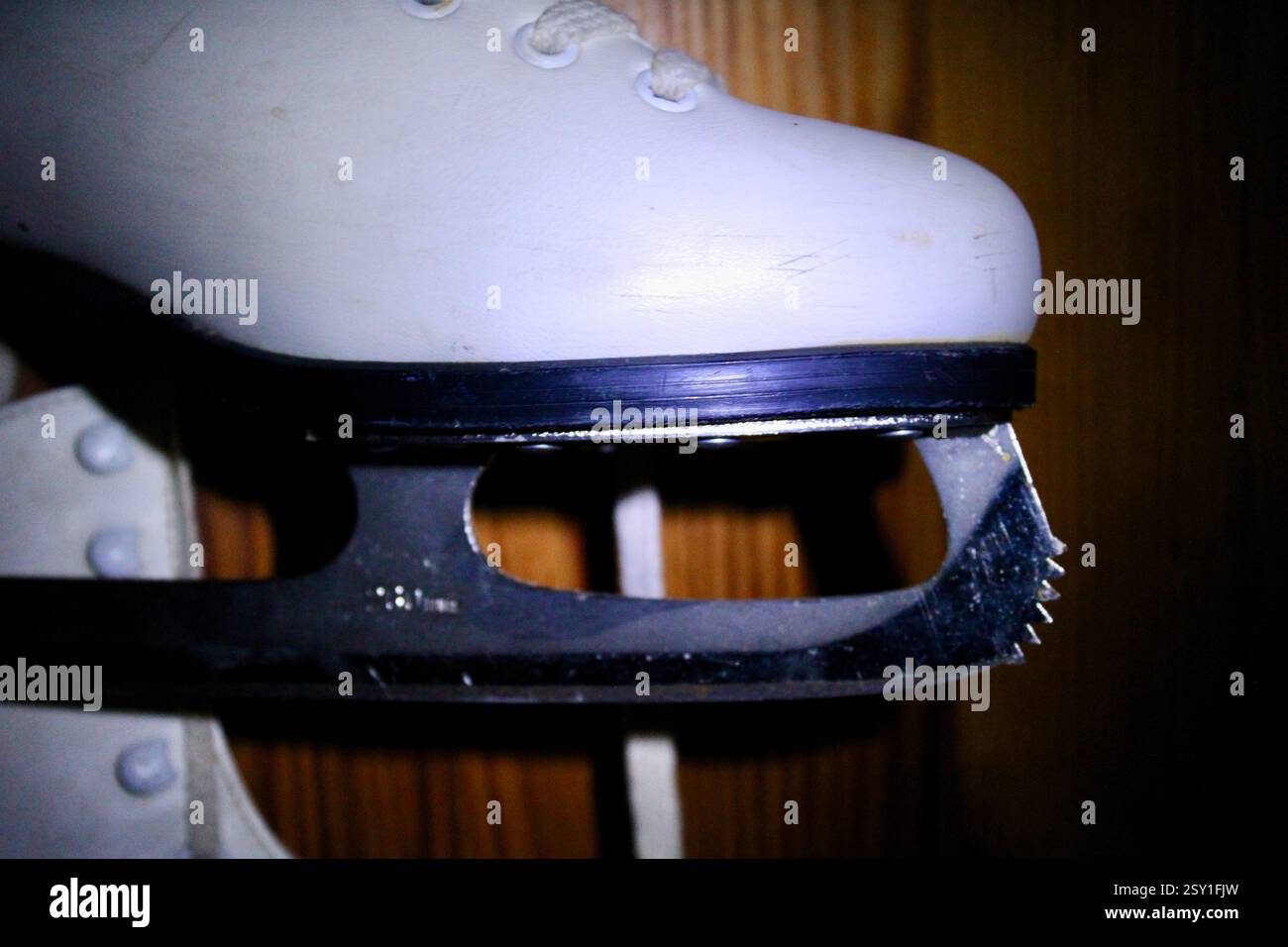 Un paio di pattini di ghiaccio in pelle bianca appesi al gancio dell'armadio in legno della camera da letto, per prepararsi agli sport invernali, scarpe sportive da donna, femminili Foto Stock