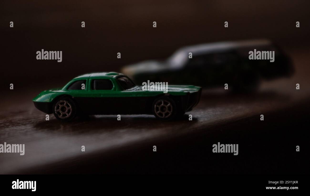 Macchinina giocattolo verde in miniatura con illuminazione spettacolare su sfondo scuro Foto Stock