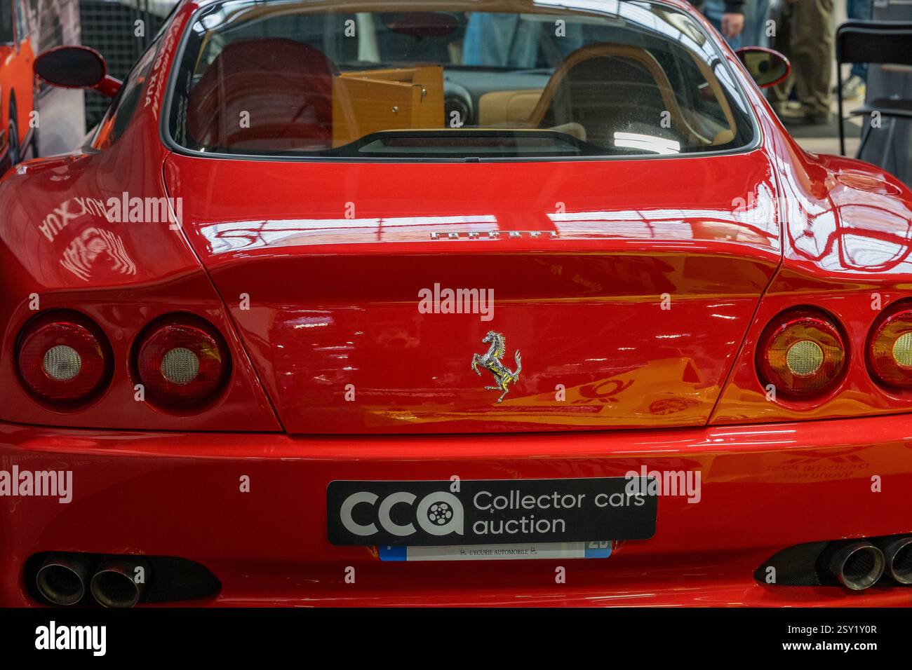 Iconica auto sportiva rossa esposta a una vivace asta di auto da collezione in un luogo di lusso durante il frenetico evento del weekend Foto Stock