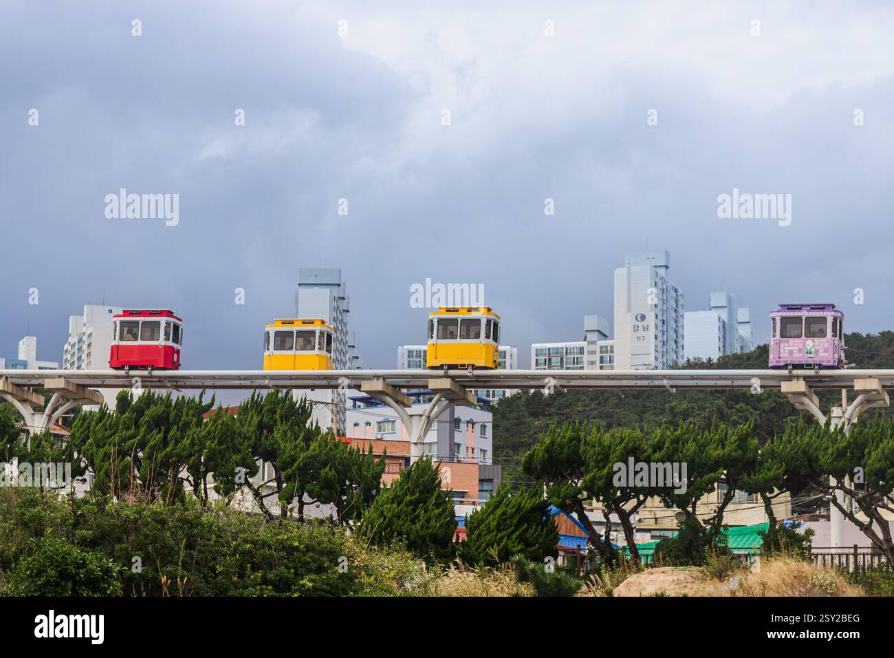 Busan, Corea del Sud - 29 ottobre 2024: Colorati treni a capsula del cielo sulla Busan Green Railway, con un sentiero a piedi e un paesaggio panoramico. Foto Stock