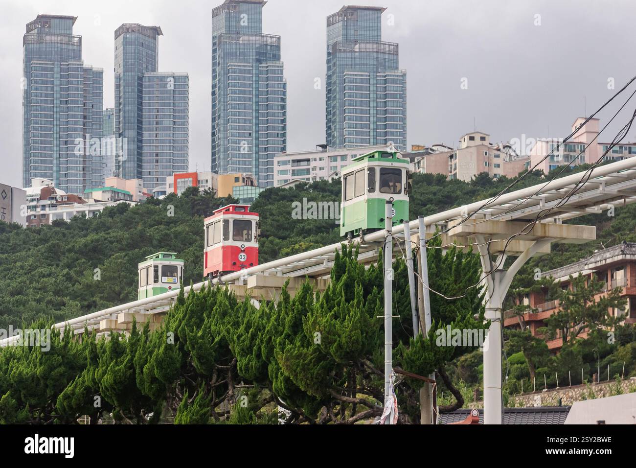 Busan, Corea del Sud - 29 ottobre 2024: Colorati treni a capsula del cielo sulla Busan Green Railway, con un sentiero a piedi e un paesaggio panoramico. Foto Stock