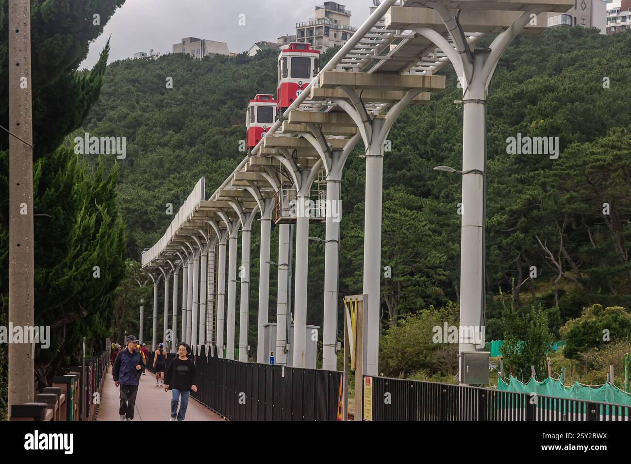 Busan, Corea del Sud - 29 ottobre 2024: Colorati treni a capsula del cielo sulla Busan Green Railway, con un sentiero a piedi e un paesaggio panoramico. Foto Stock