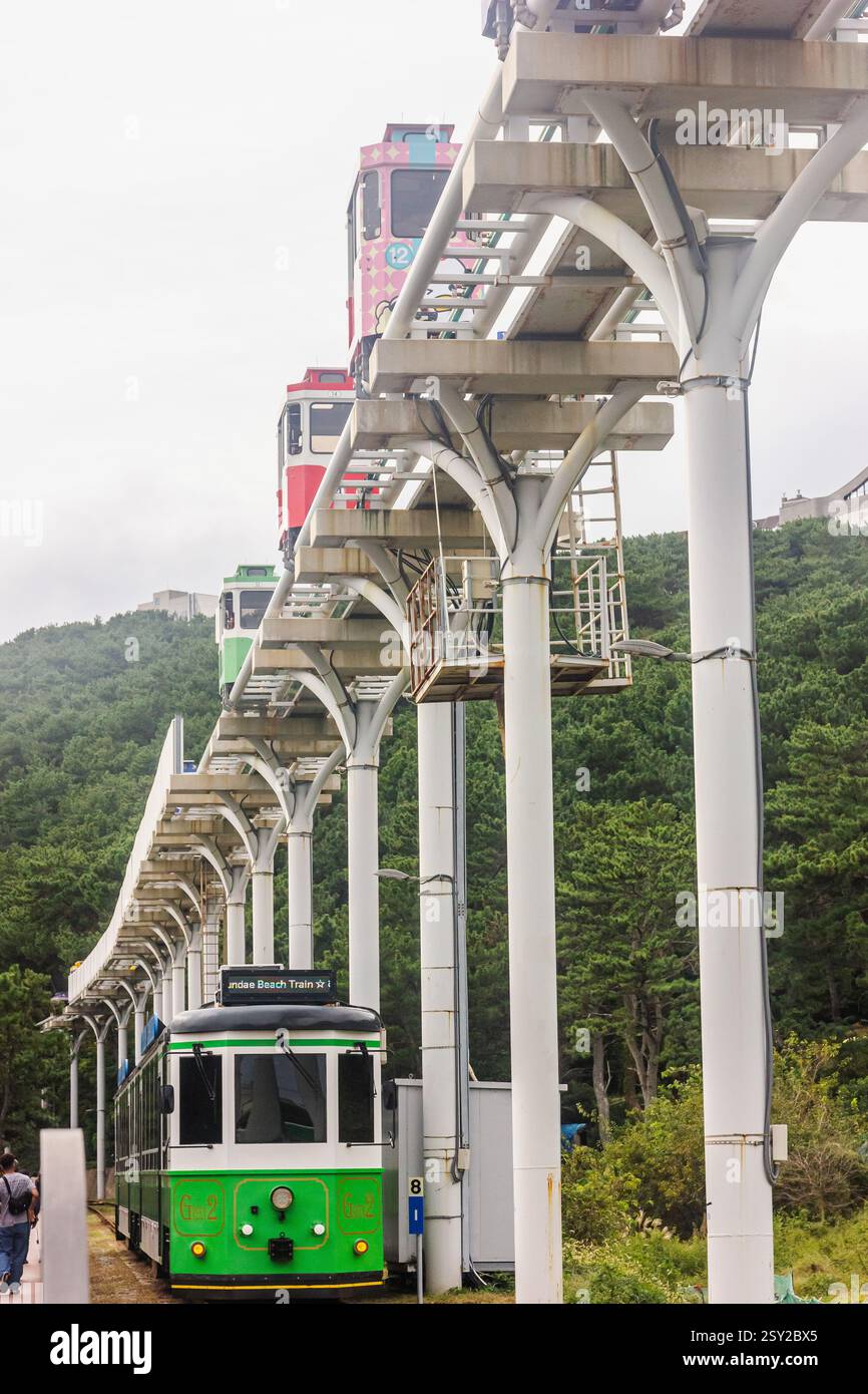 Busan, Corea del Sud - 29 ottobre 2024: Treno sulla spiaggia di Haeundae e treni colorati a capsula del cielo sulla Busan Green Railway a Busan. Foto Stock