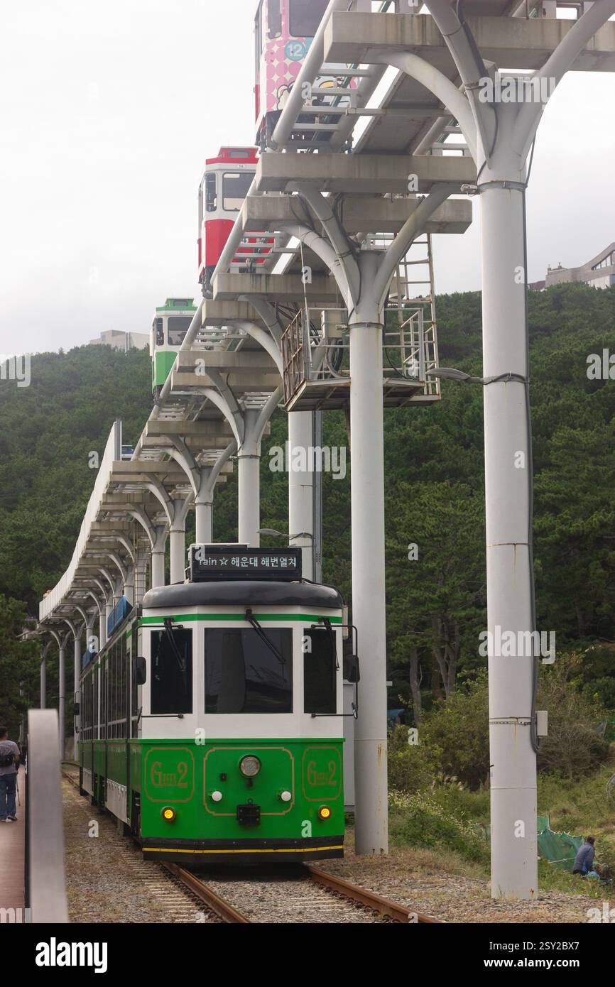 Busan, Corea del Sud - 29 ottobre 2024: Treno sulla spiaggia di Haeundae e treni colorati a capsula del cielo sulla Busan Green Railway a Busan. Foto Stock
