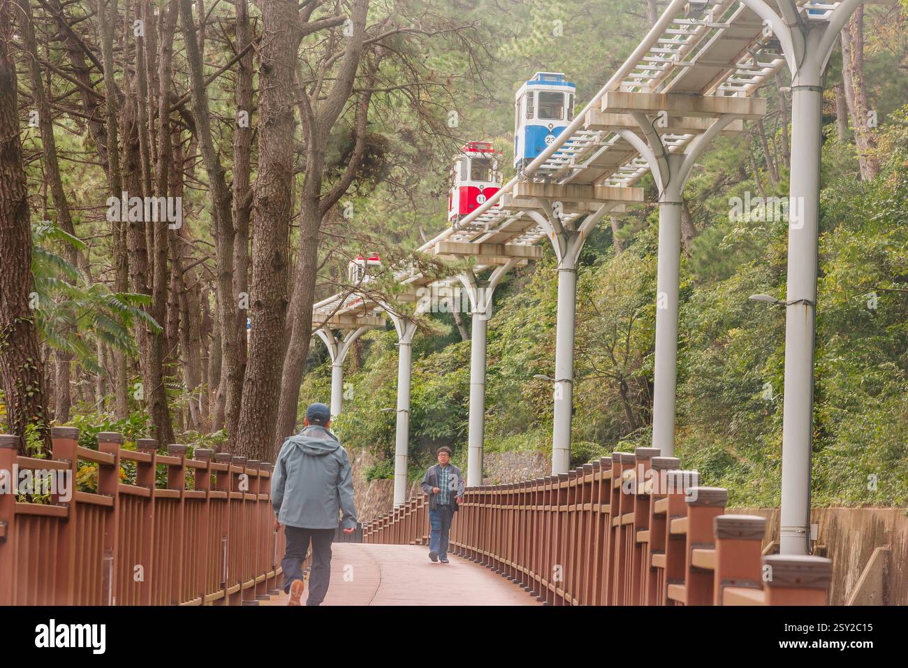 Busan, Corea del Sud - 29 ottobre 2024: Colorati treni a capsula del cielo sulla Busan Green Railway, con un sentiero a piedi e un paesaggio panoramico. Foto Stock