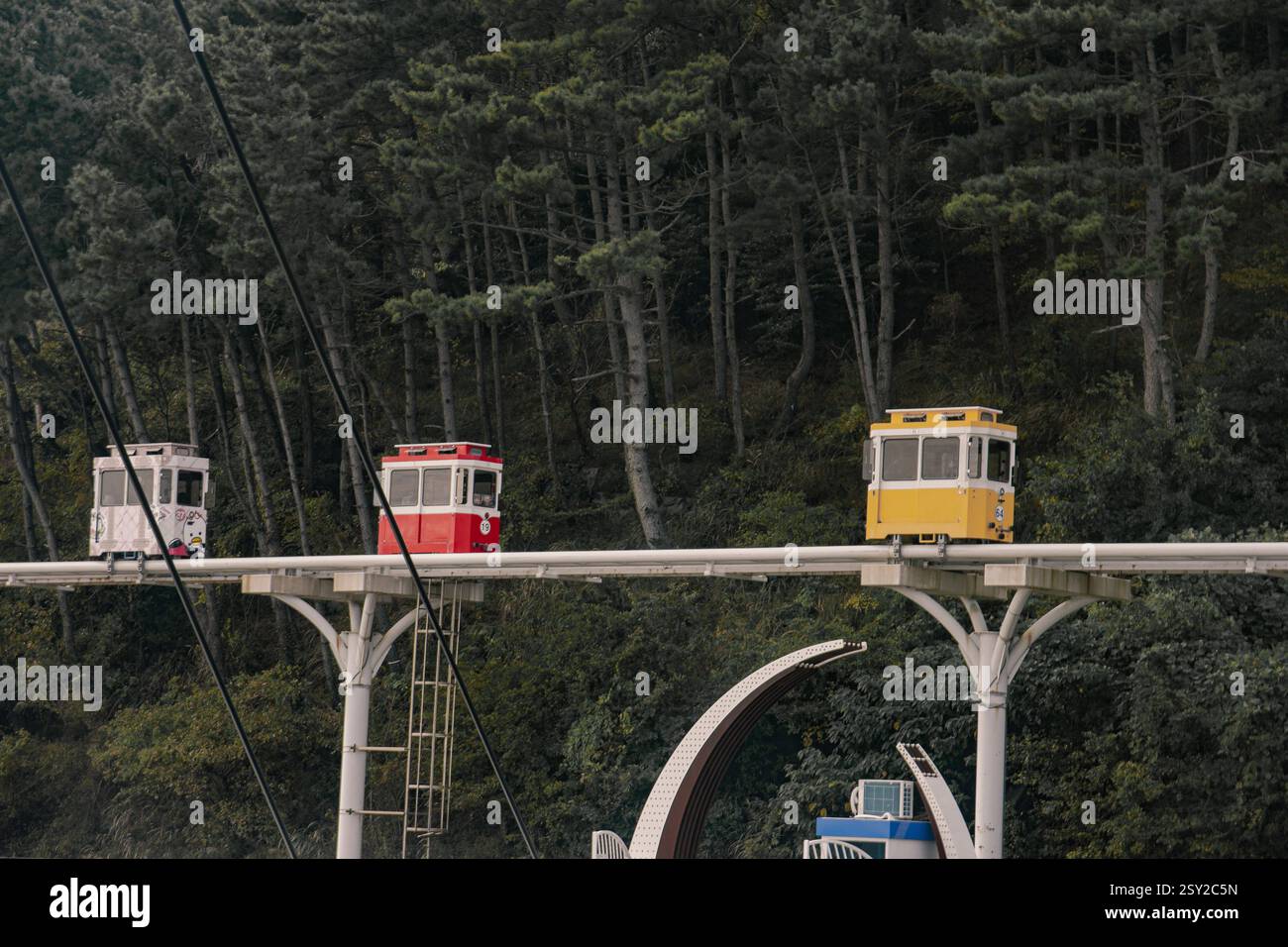 Busan, Corea del Sud - 29 ottobre 2024: Colorati treni a capsula del cielo sulla Busan Green Railway, con un sentiero a piedi e un paesaggio panoramico. Foto Stock