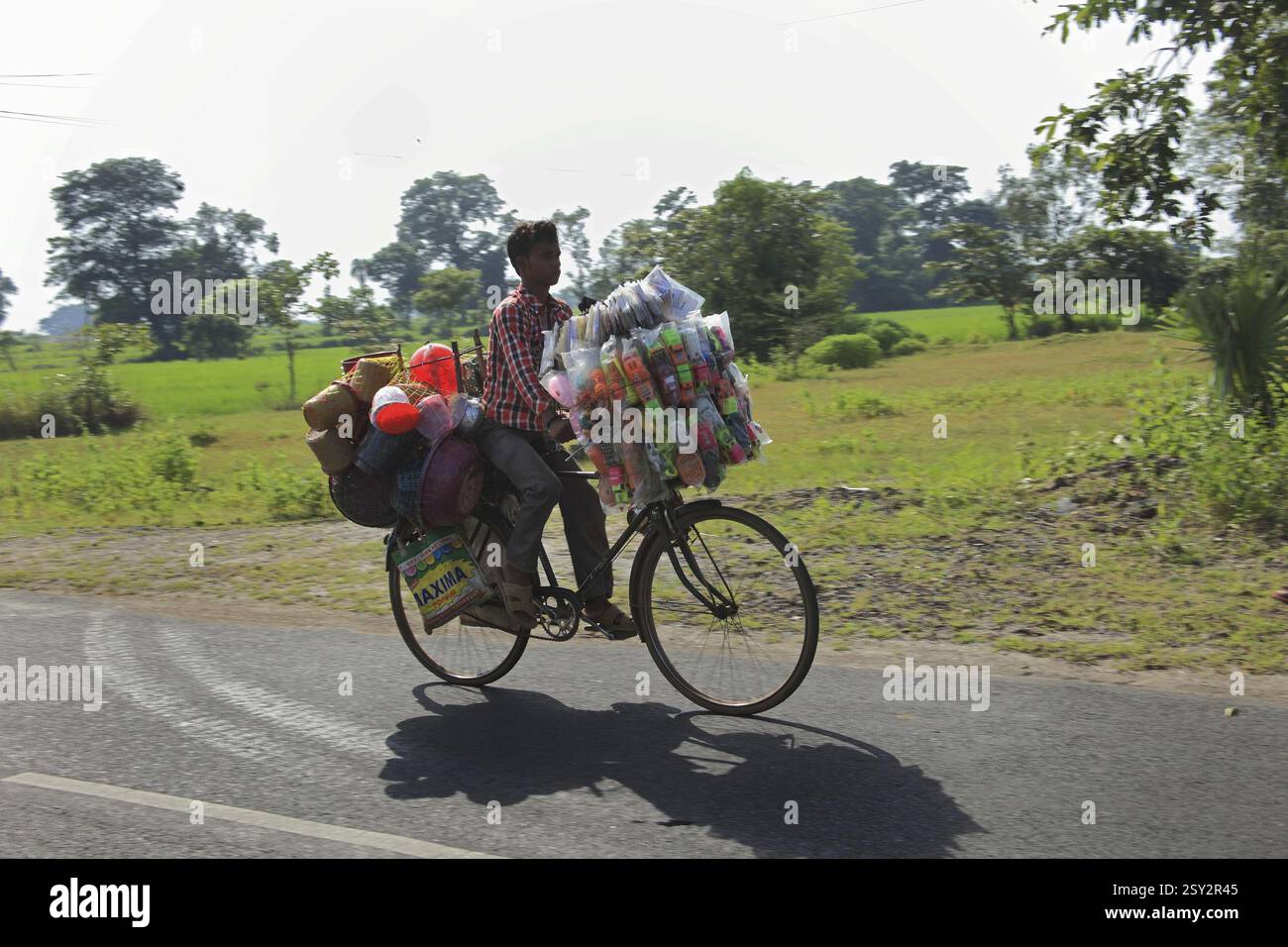 Uomo che trasporta giocattoli di plastica in vendita in bicicletta a Sambalpur Orissa India Foto Stock