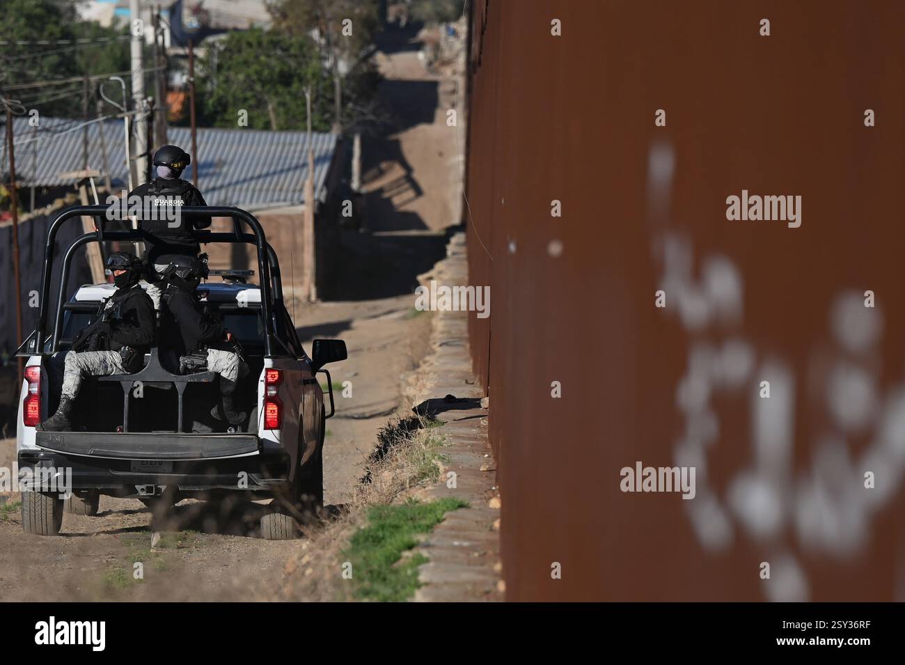 Tijuana, bassa California, Messico. 26 febbraio 2025. I membri della Guardia nazionale messicana che pattugliano la barriera di confine tra Stati Uniti e Messico nella parte orientale di Tijuana, bassa California, Messico, mercoledì 26 febbraio, 2025. il governo del Messico ha iniziato a inviare truppe al confine settentrionale con gli Stati Uniti all'inizio di febbraio come parte di un'operazione di dispiegamento di 000 membri per rafforzare le misure contro la migrazione illegale e il contrabbando transfrontaliero di droga, in cui il presidente messicano Claudia Sheinbaum ha promesso alla sua controparte americana il presidente Donald Trump in cambio di un ritardo delle sue tariffe, che sono state dela Foto Stock