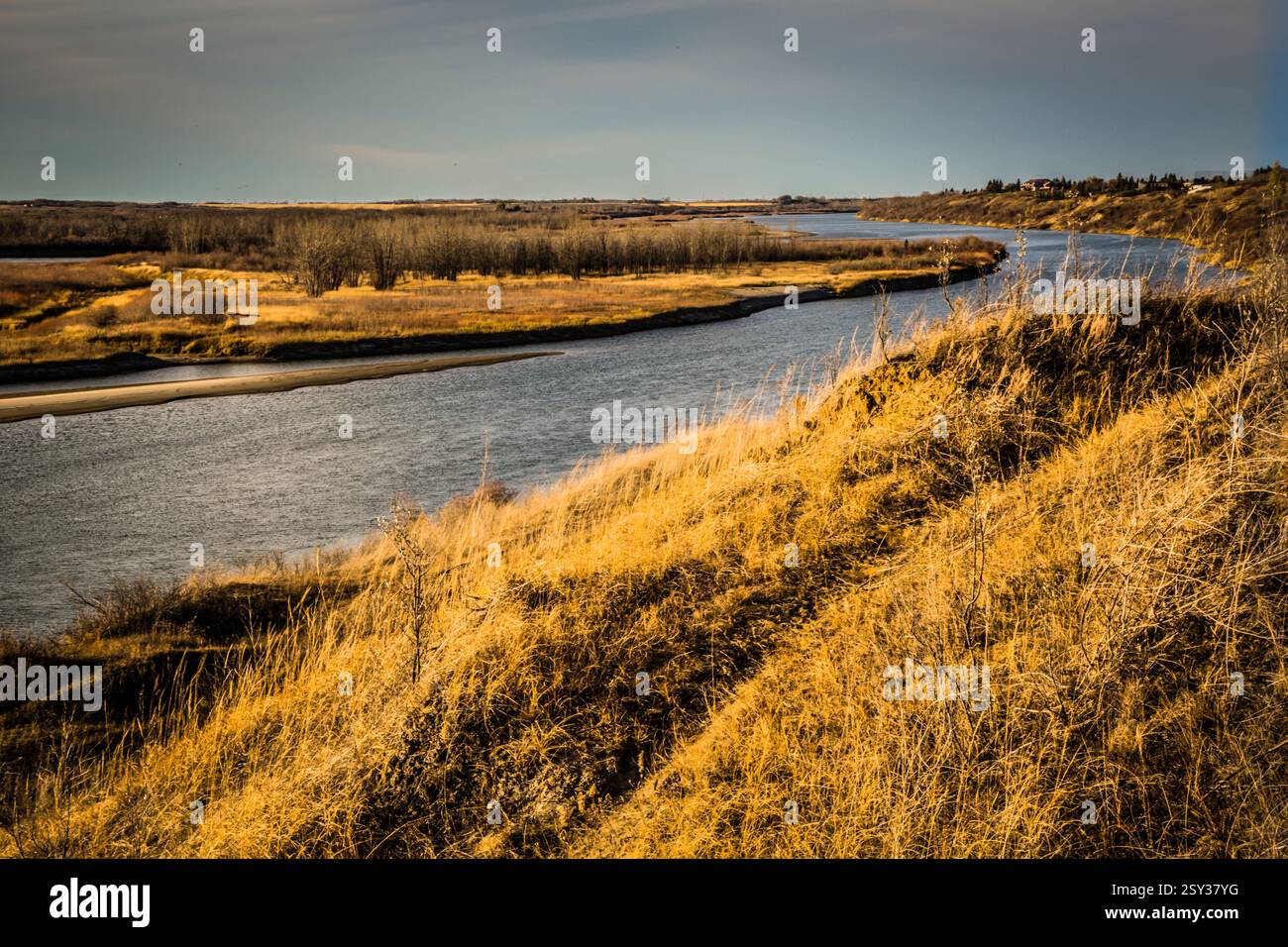 Fiume con una riva sabbiosa. L'acqua è marrone. C'è una collina con l'erba Foto Stock