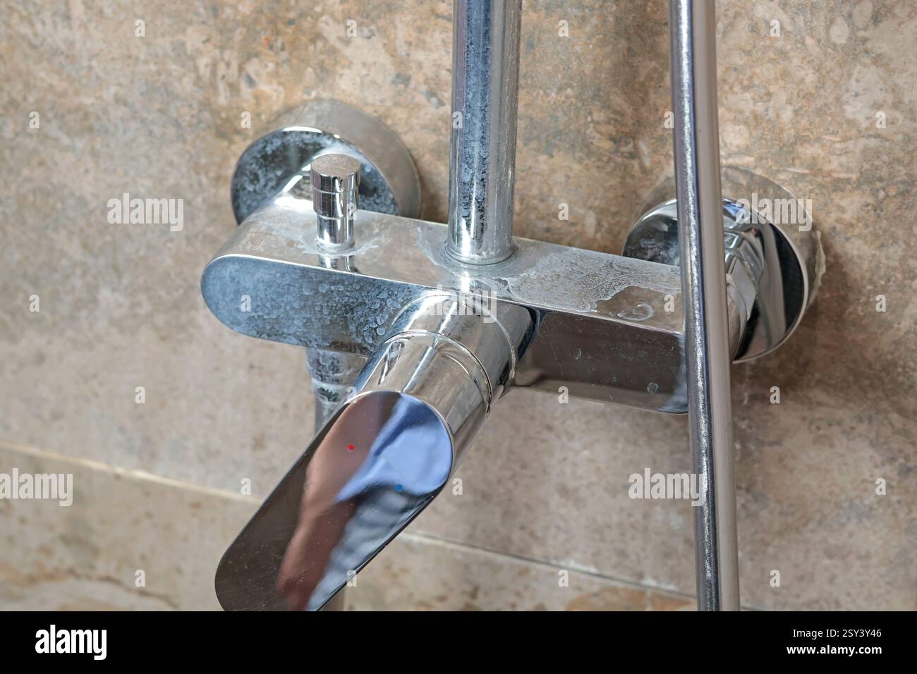 Rubinetto sporco con depositi di sale dall'acqua in bagno su moderne piastrelle scure in marmo. Pulizia e pulizia. Cura della casa e dell'ordine. Stile di vita. Foto Stock