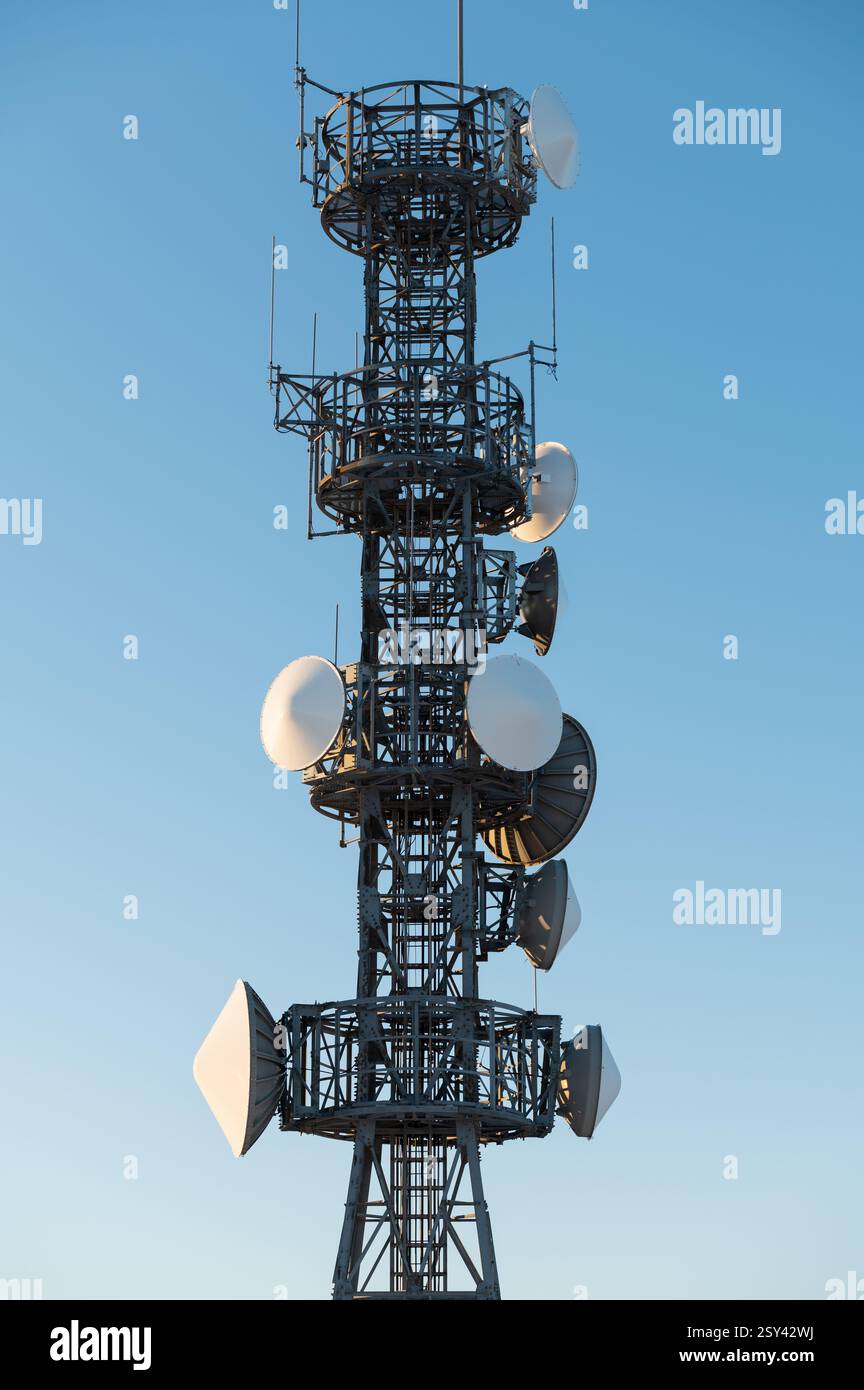 Torre di telecomunicazione per primo piano con parabole satellitari su sfondo blu Foto Stock