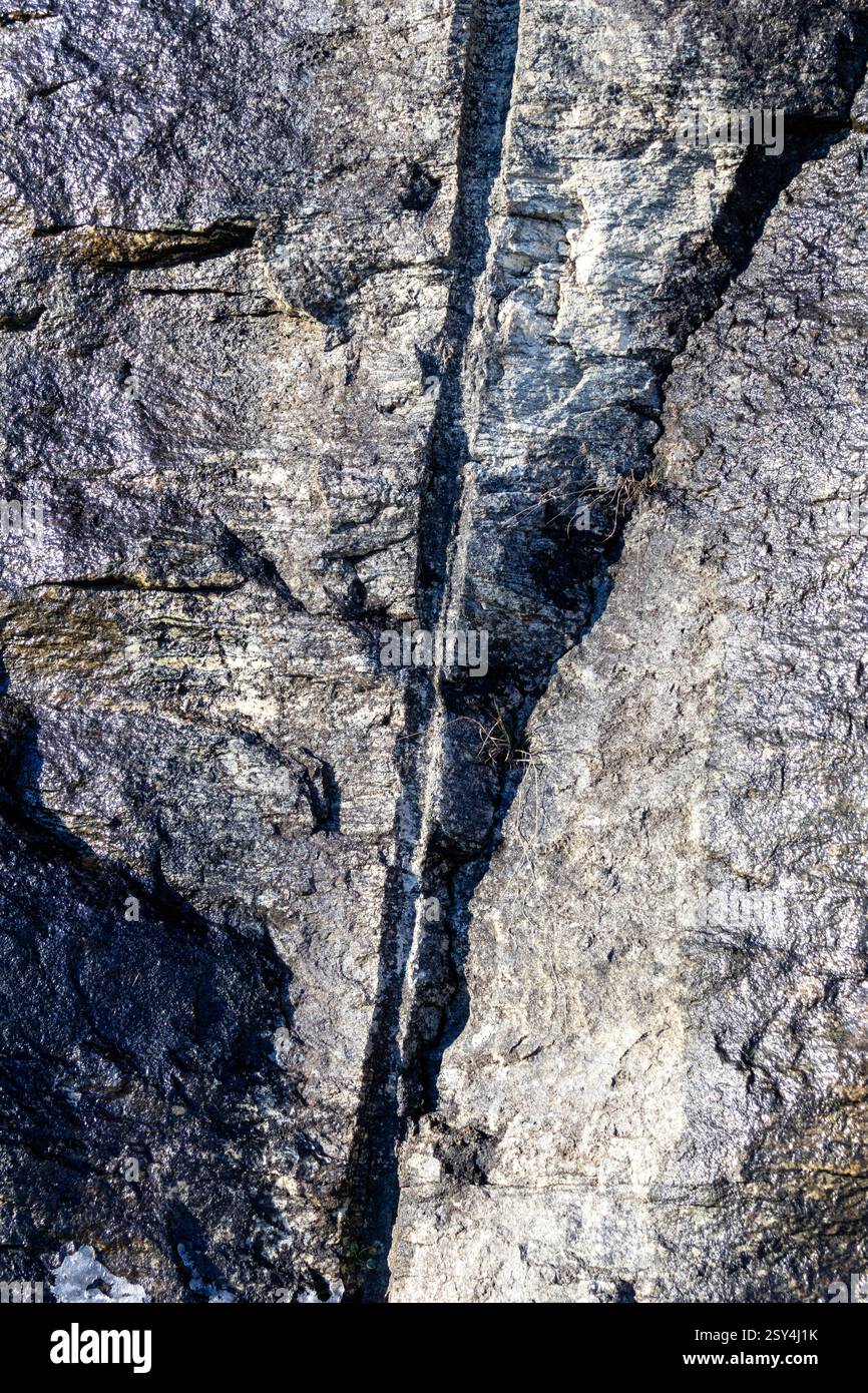 Una frattura nel tempo, dove la pietra incontra l'acciaio, dove la forza svela la la storia silenziosa all'interno. Strati di storia esposti nel cuore della roccia Foto Stock