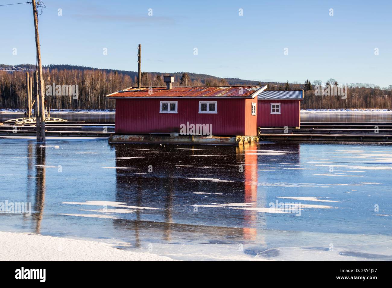 Sentieri ghiacciati: I pontoni riposano sul ghiaccio, portando a boatouses racchiuse nella morsa invernale, i loro riflessi scintillano sotto il luminoso sole invernale Foto Stock