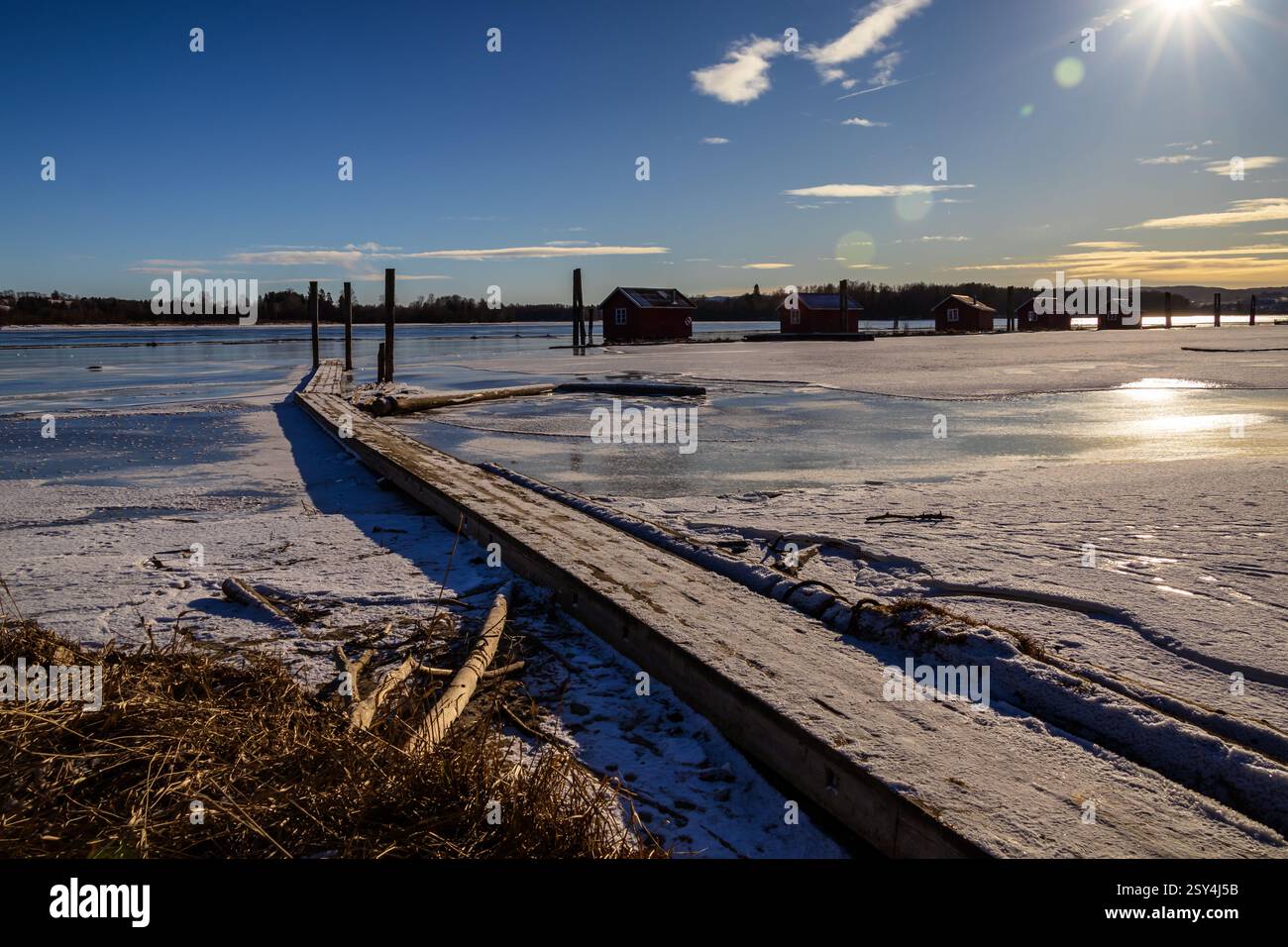 Sentieri ghiacciati: I pontoni riposano sul ghiaccio, portando a boatouses racchiuse nella morsa invernale, i loro riflessi scintillano sotto il luminoso sole invernale Foto Stock