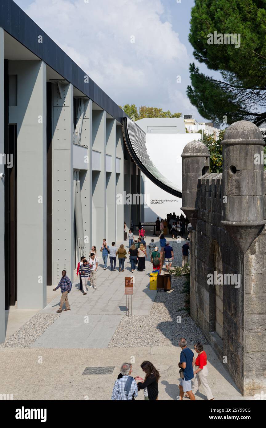 I visitatori camminano tra la storica fortezza in pietra e l'elegante architettura curva del nuovo centro d'arte Foto Stock