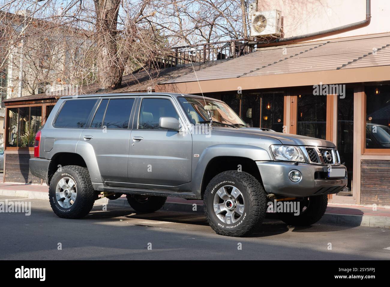 Bucarest, Romania – 14 febbraio 2025: Vista frontale della Nissan Patrol auto fuoristrada argentata parcheggiata di fronte a un pub Foto Stock
