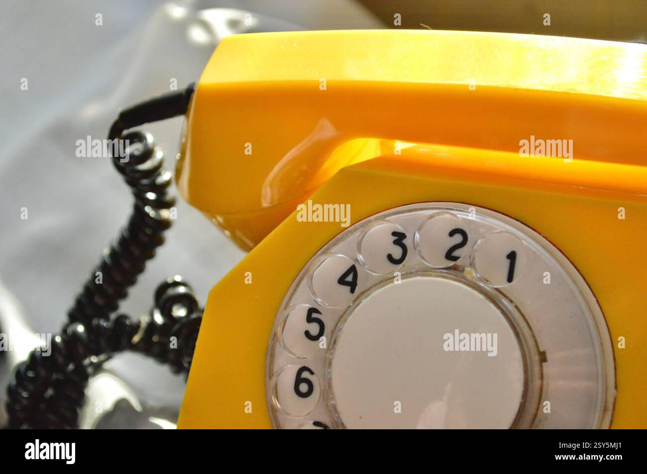 Primo piano di un telefono rotante giallo che evoca il fascino vintage e il design classico delle comunicazioni Foto Stock