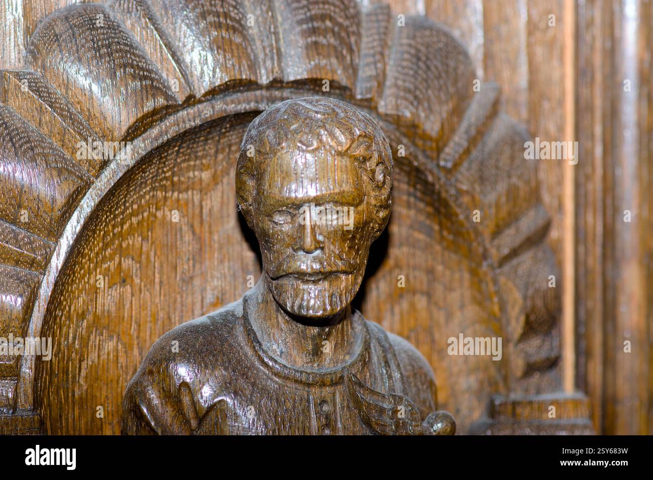 Una finemente dettagliata scultura in legno del ritratto di un mercante adorna un antico armadio in quercia tedesca. La lavorazione artigianale è caratterizzata da dettagli complessi ed elementi di rilievo Foto Stock