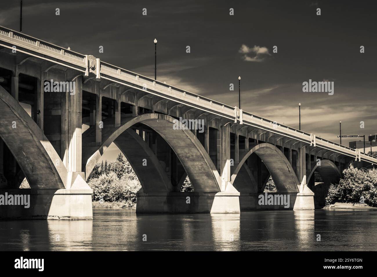 Ponte con un grande arco al centro. Il ponte è sopra un fiume. Ci sono due luci sul ponte Foto Stock