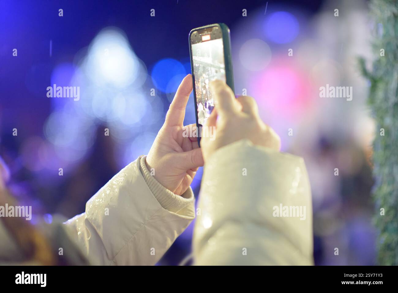 Una donna fotografa il vivace mercatino di Natale di Craiova di notte con luci accese decorazioni colorate e amata festa rumena tradizionale Foto Stock