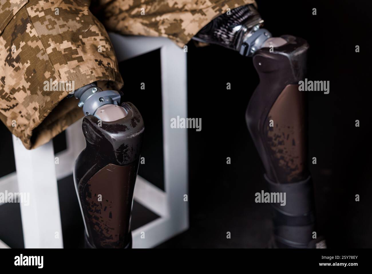 Dettaglio della protesi bionica delle gambe di un uomo in pantaloni mimetici militari. Foto Stock
