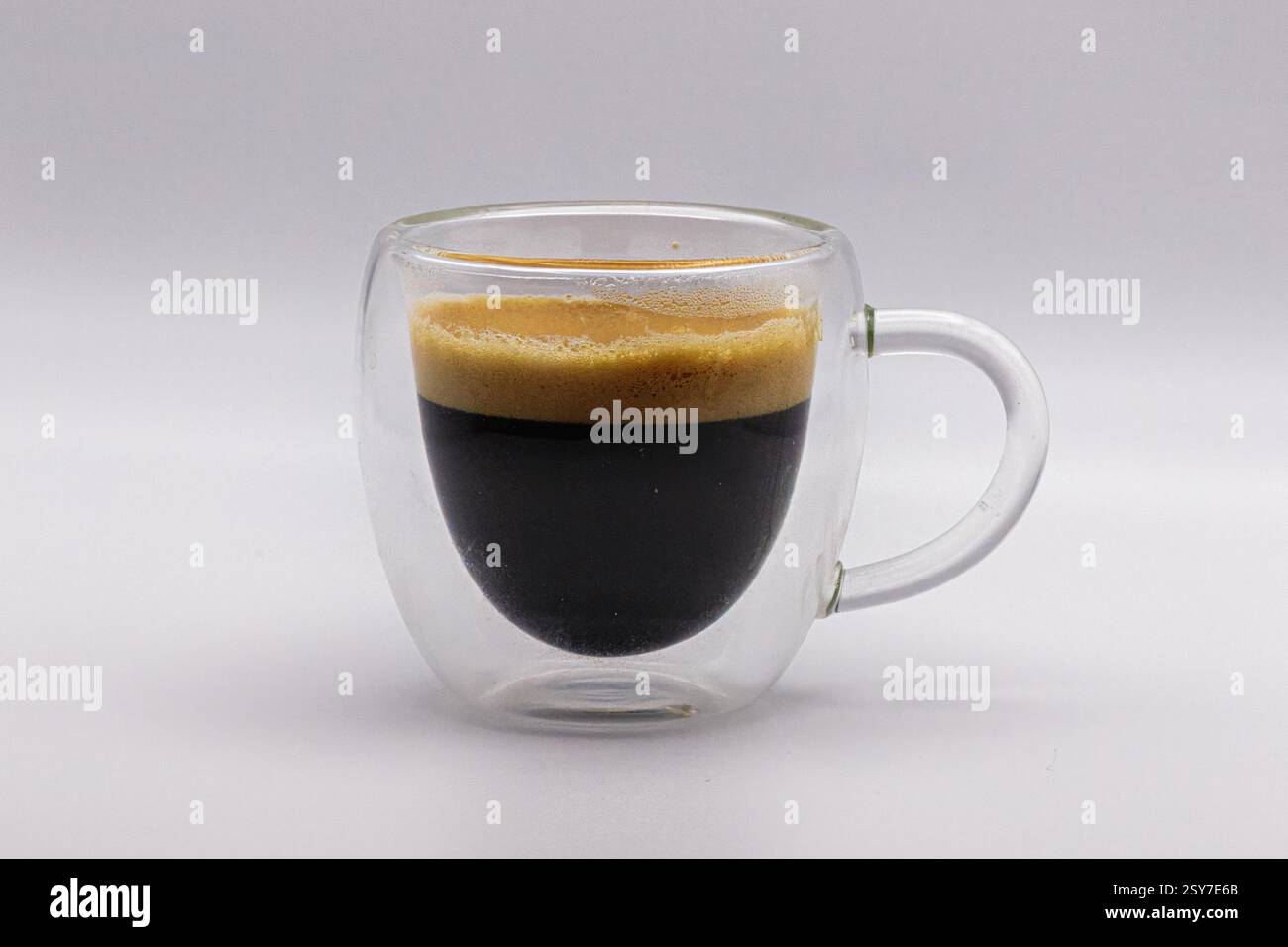 Un espresso doppio, isolato in una tazza di caffè trasparente. Foto Stock